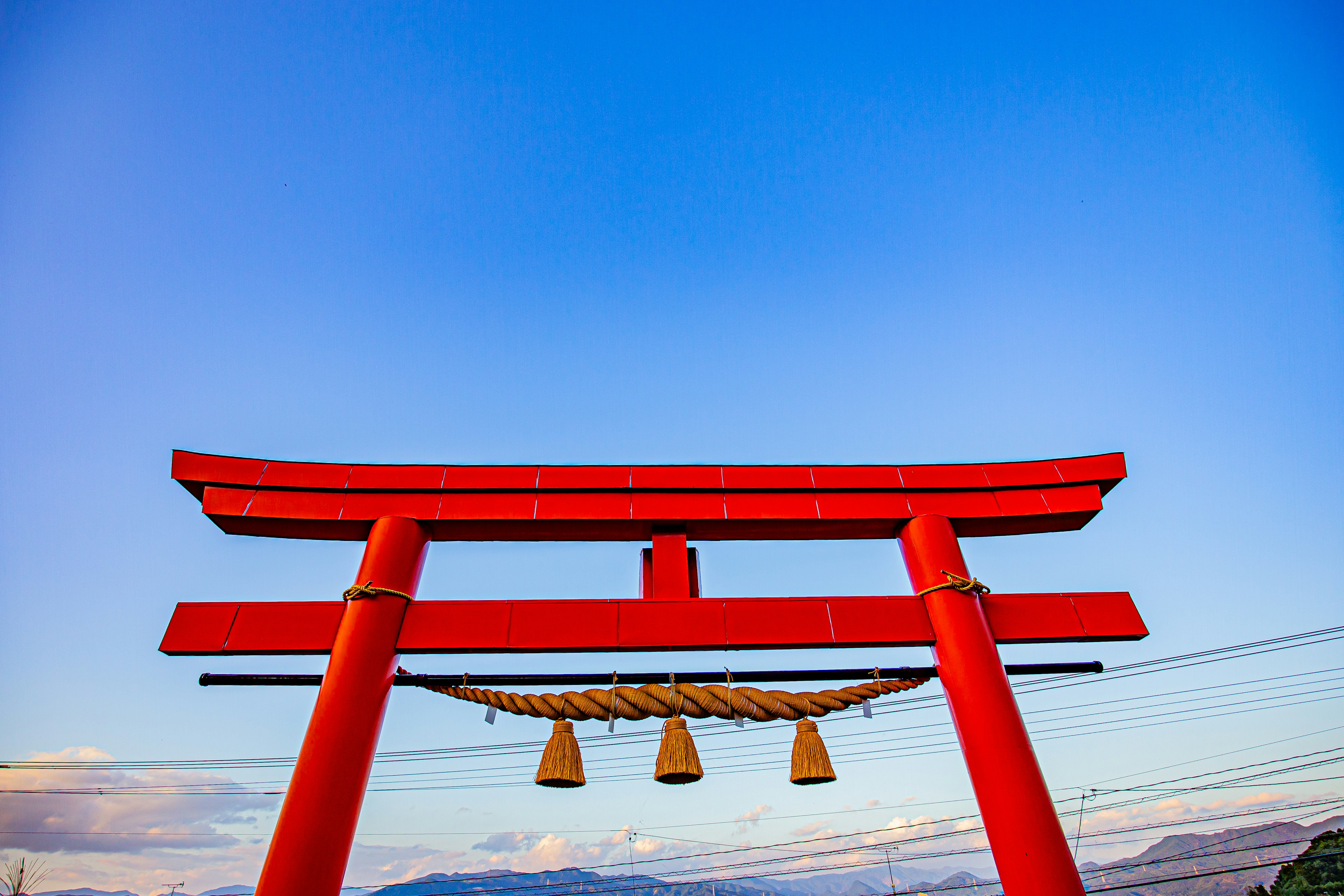 Red torii gate standing under a blue sky