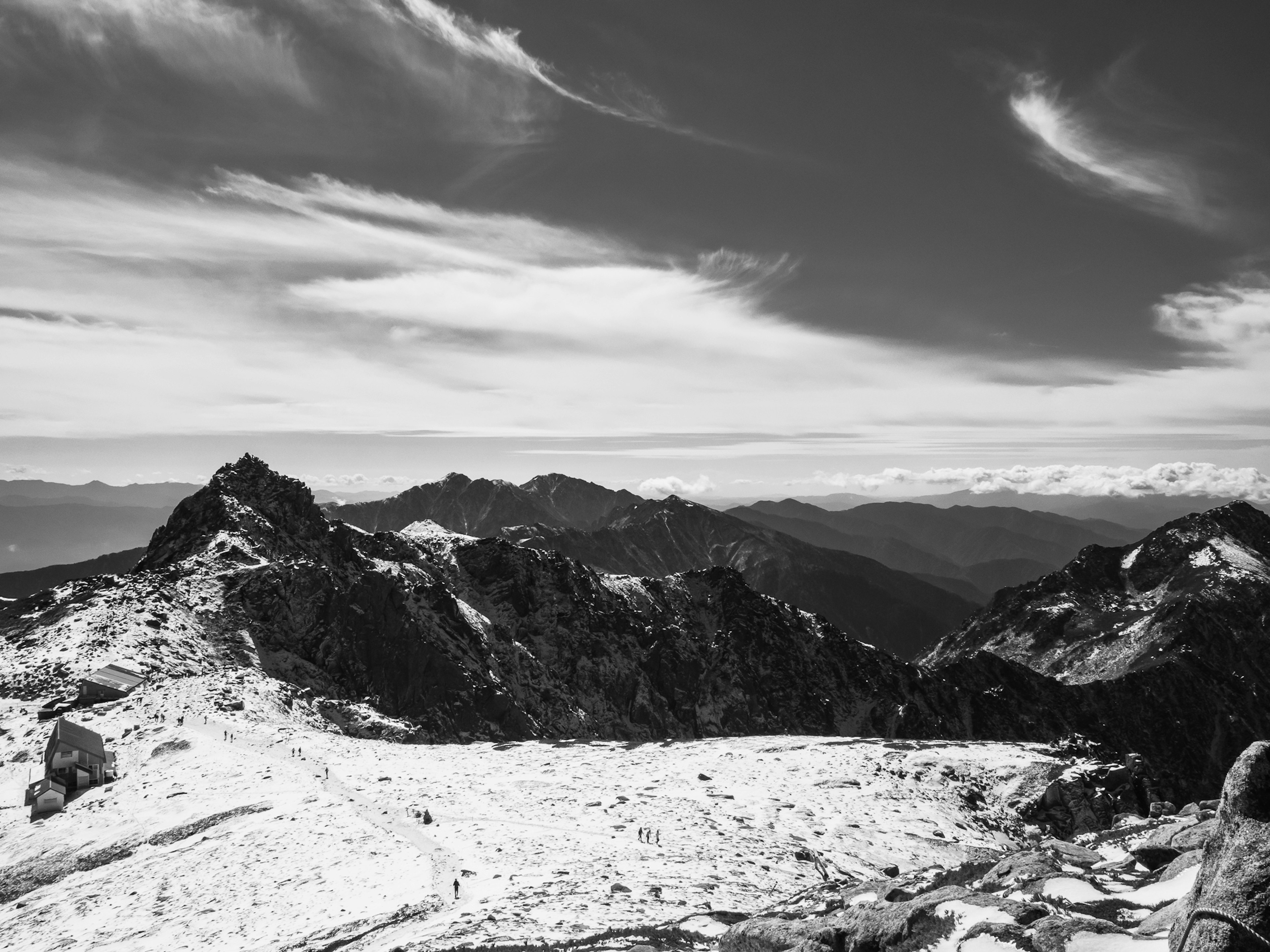 Paesaggio montano in bianco e nero con nuvole ampie e cime innevate