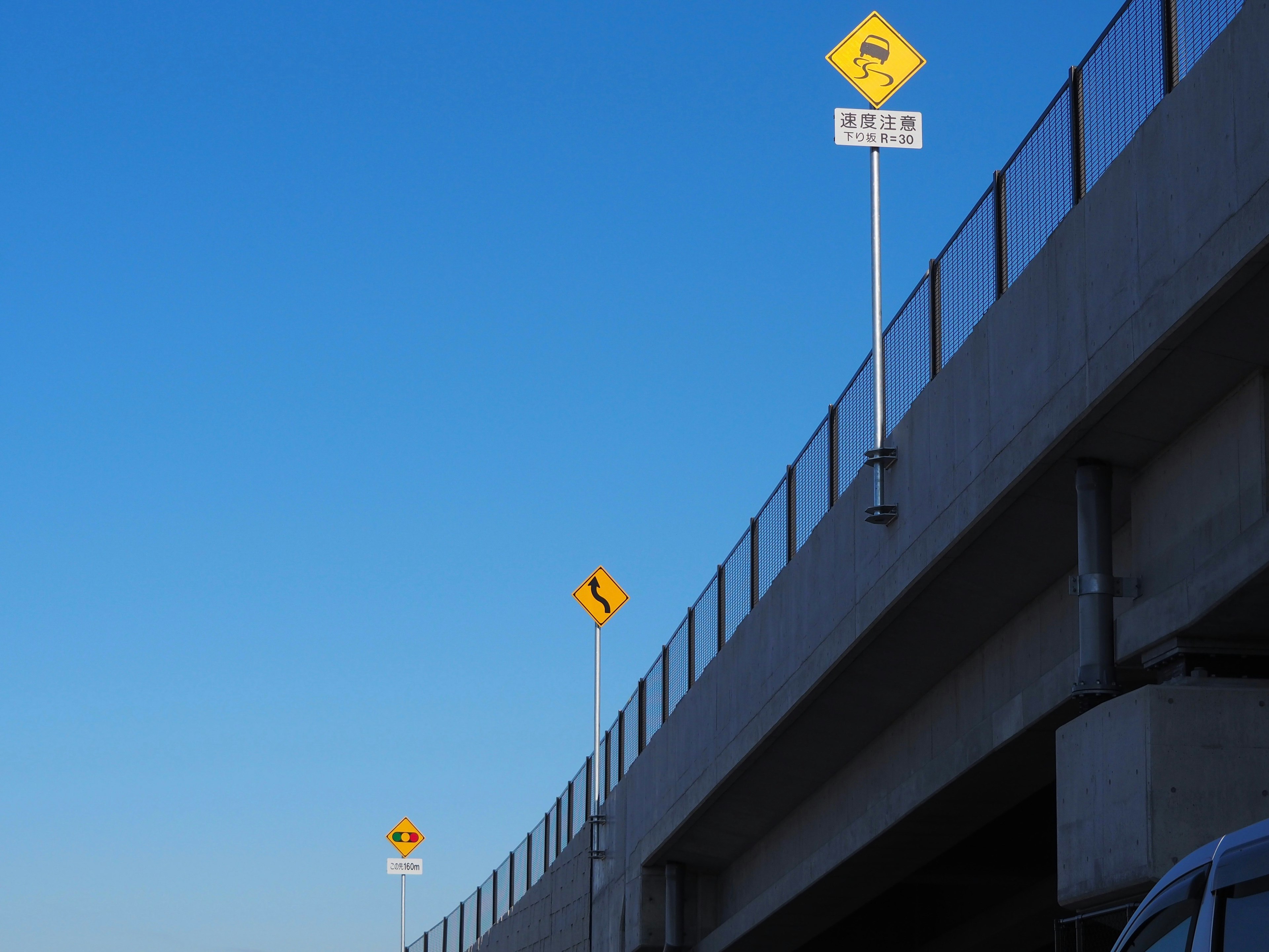 Image of road signs and an elevated bridge under a blue sky