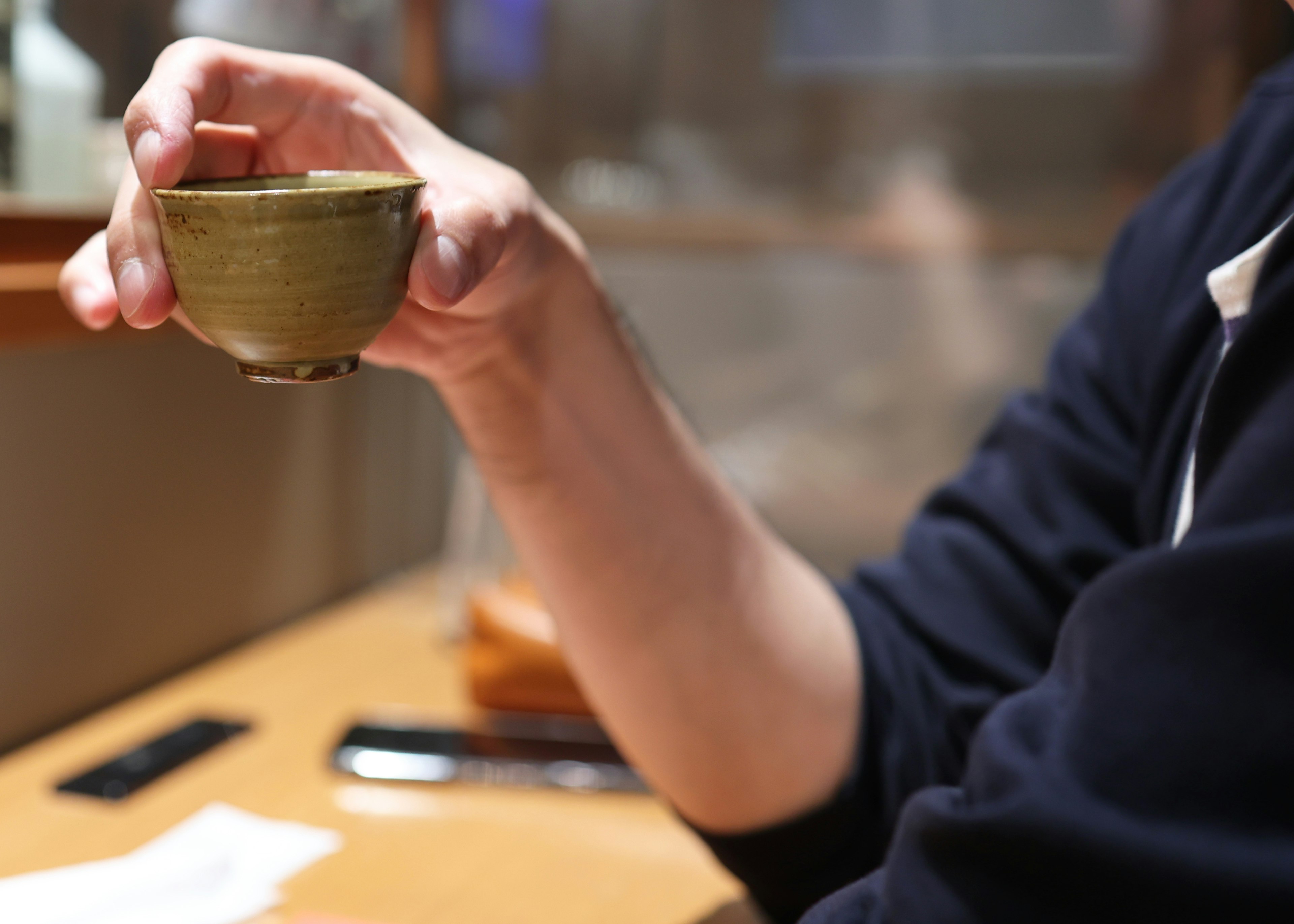 A hand holding a green tea bowl