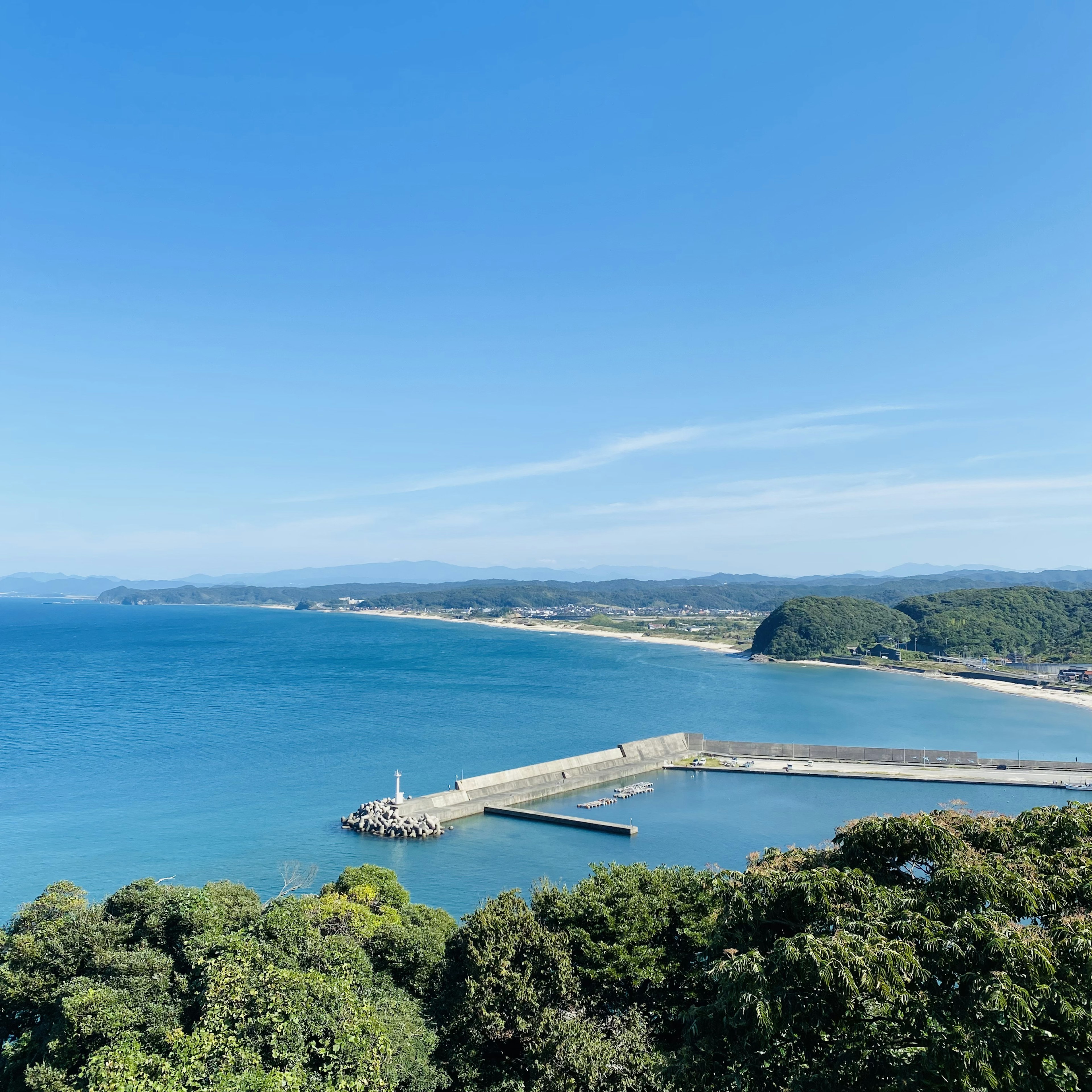 青い海と広がる空のパノラマビュー　港と防波堤が見える風景