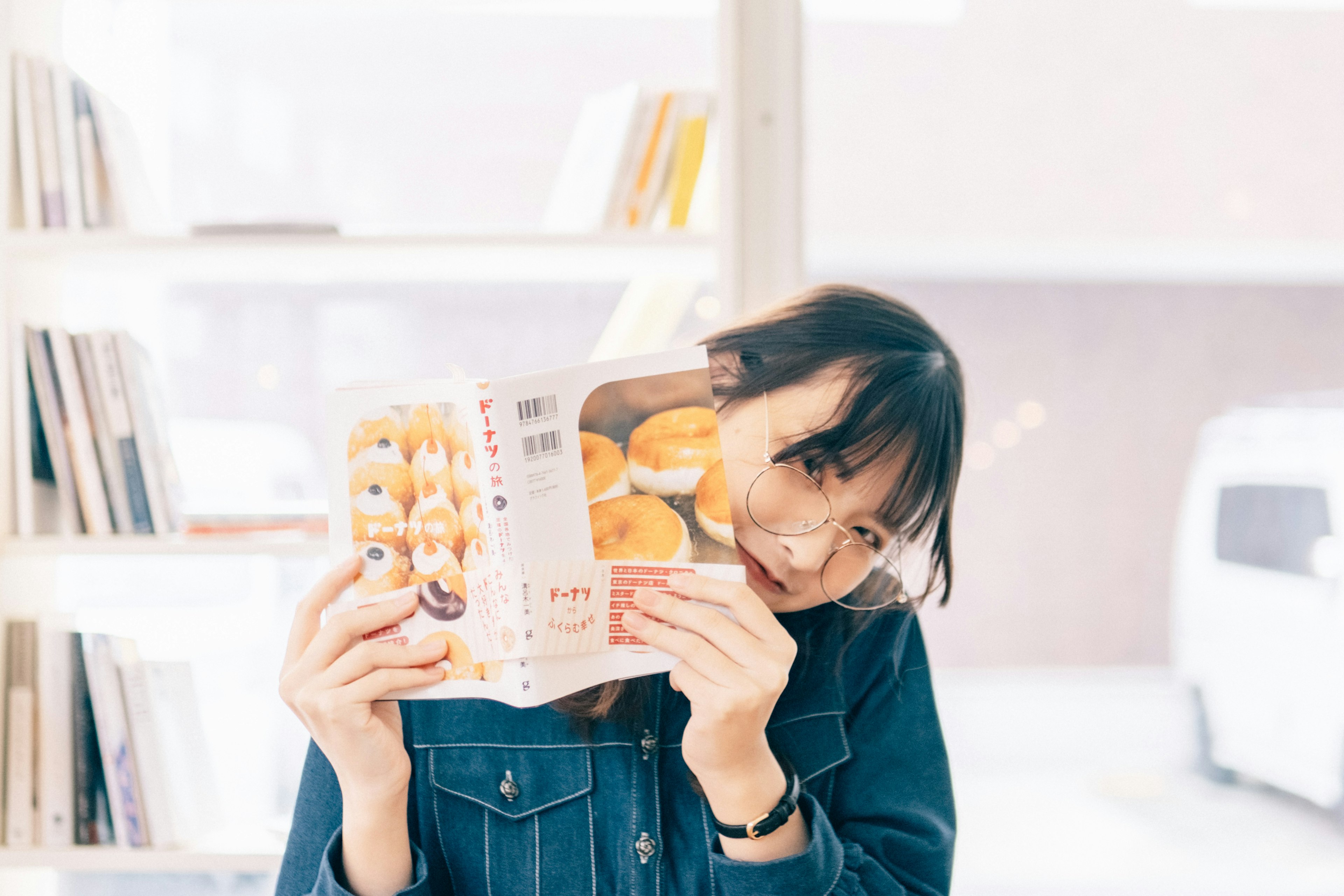 Une femme souriante tenant un livre dans un espace lumineux