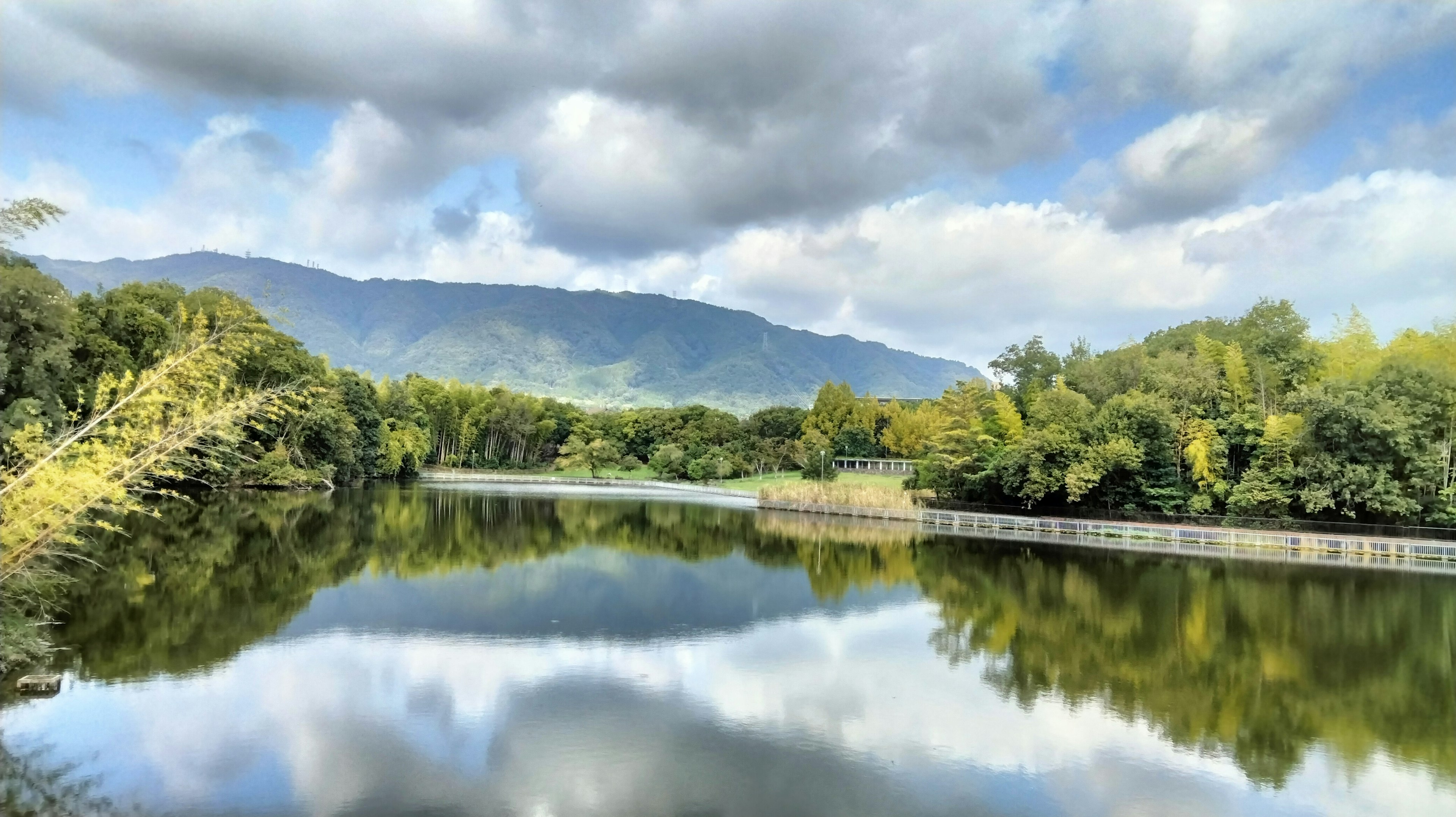 Lanskap sungai yang tenang dengan pepohonan rimbun Pantulan indah pegunungan dan awan