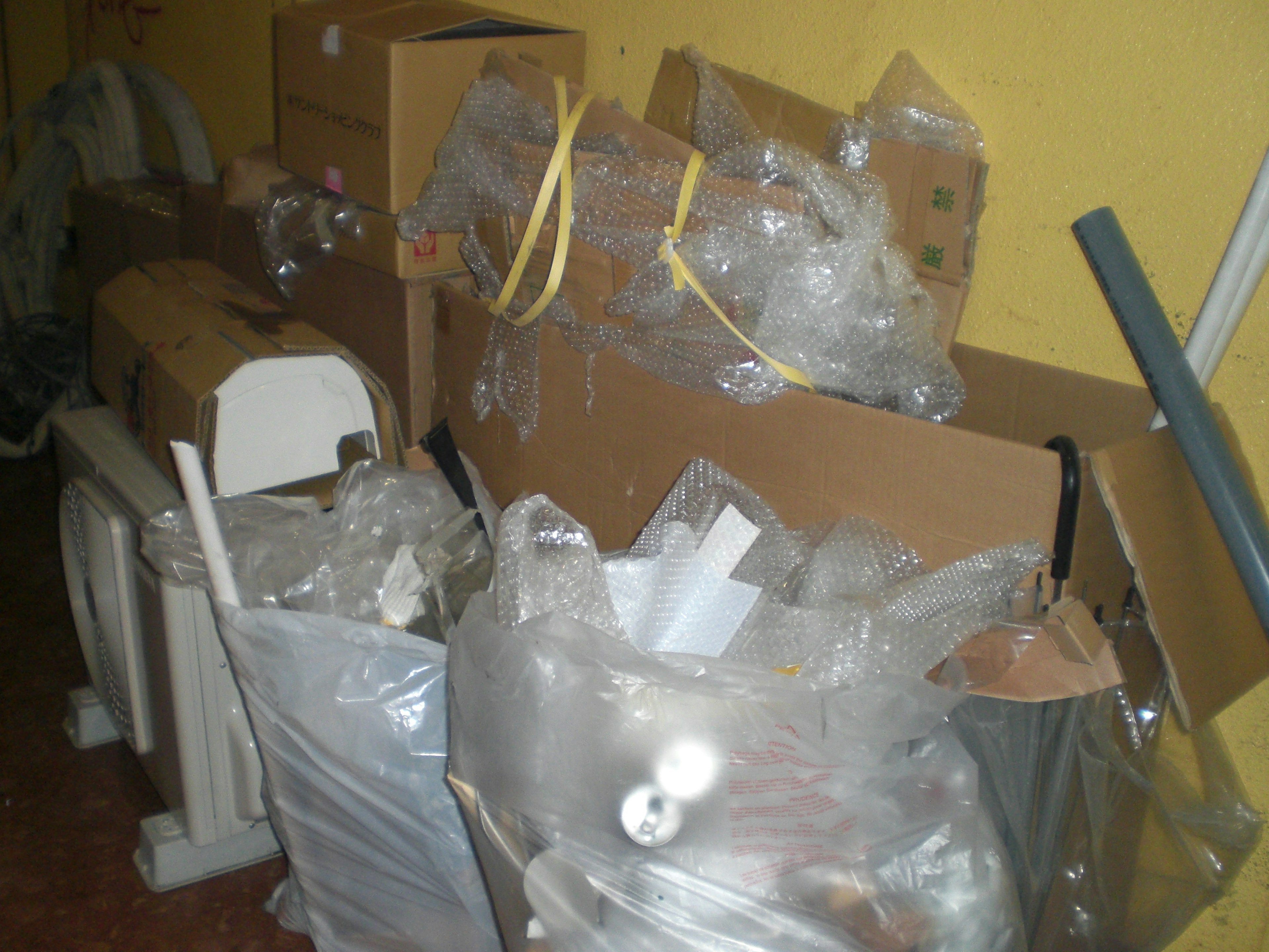 Corner of a room filled with stacked cardboard boxes and plastic bags