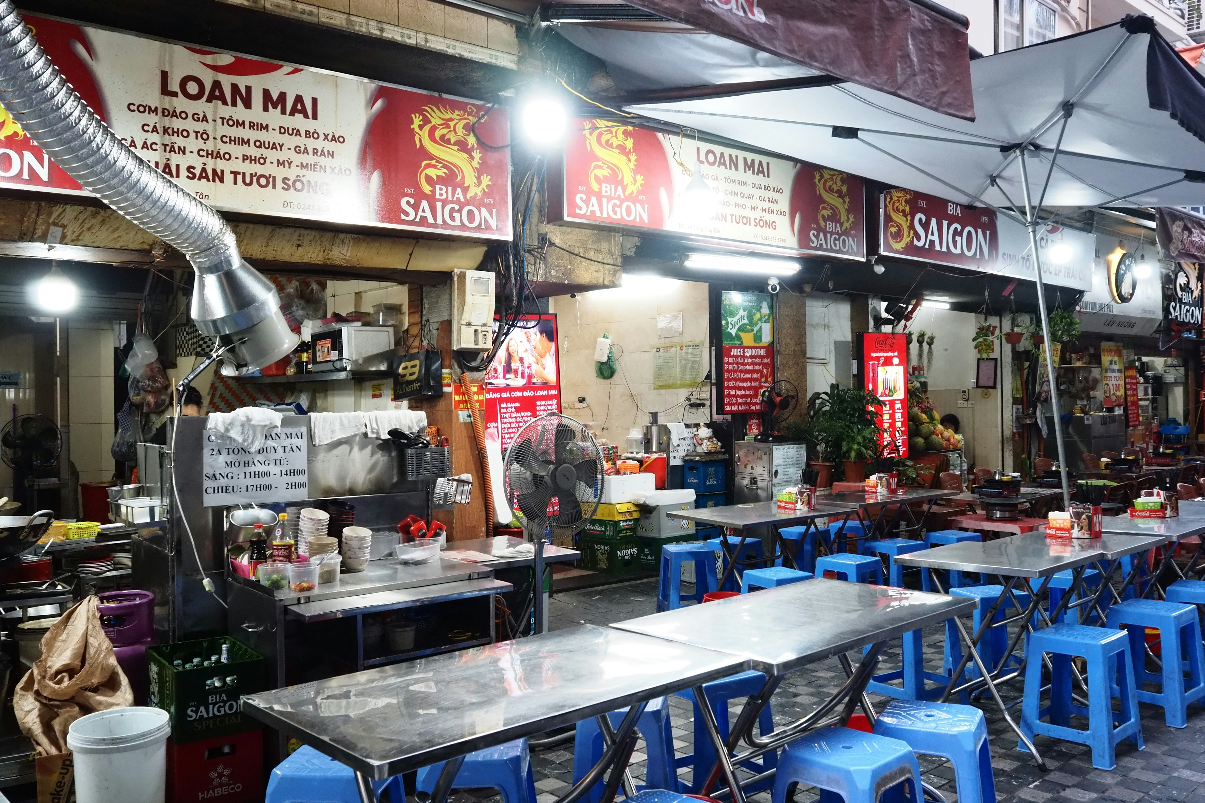 Puestos de comida callejera al aire libre con sillas y mesas azules