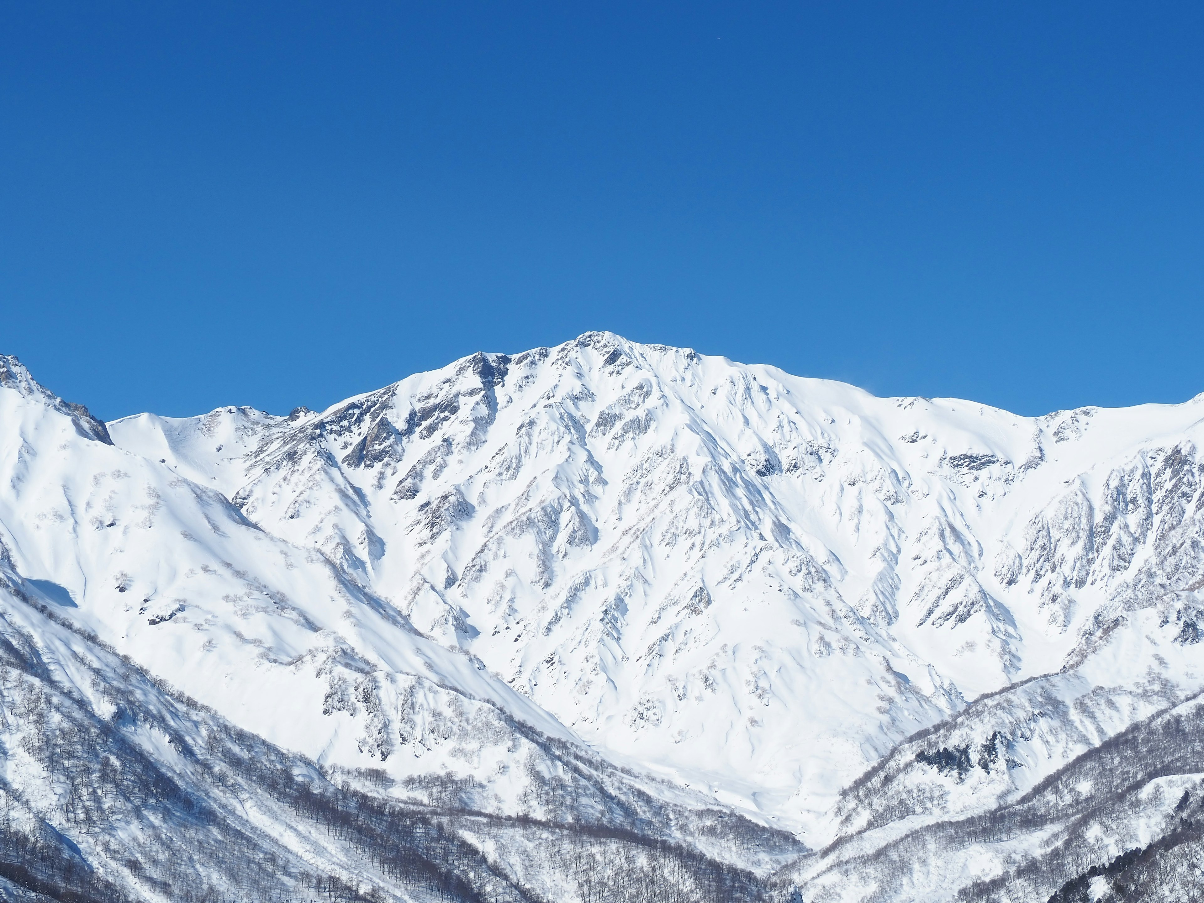 雪覆盖的山脉在晴朗的蓝天下