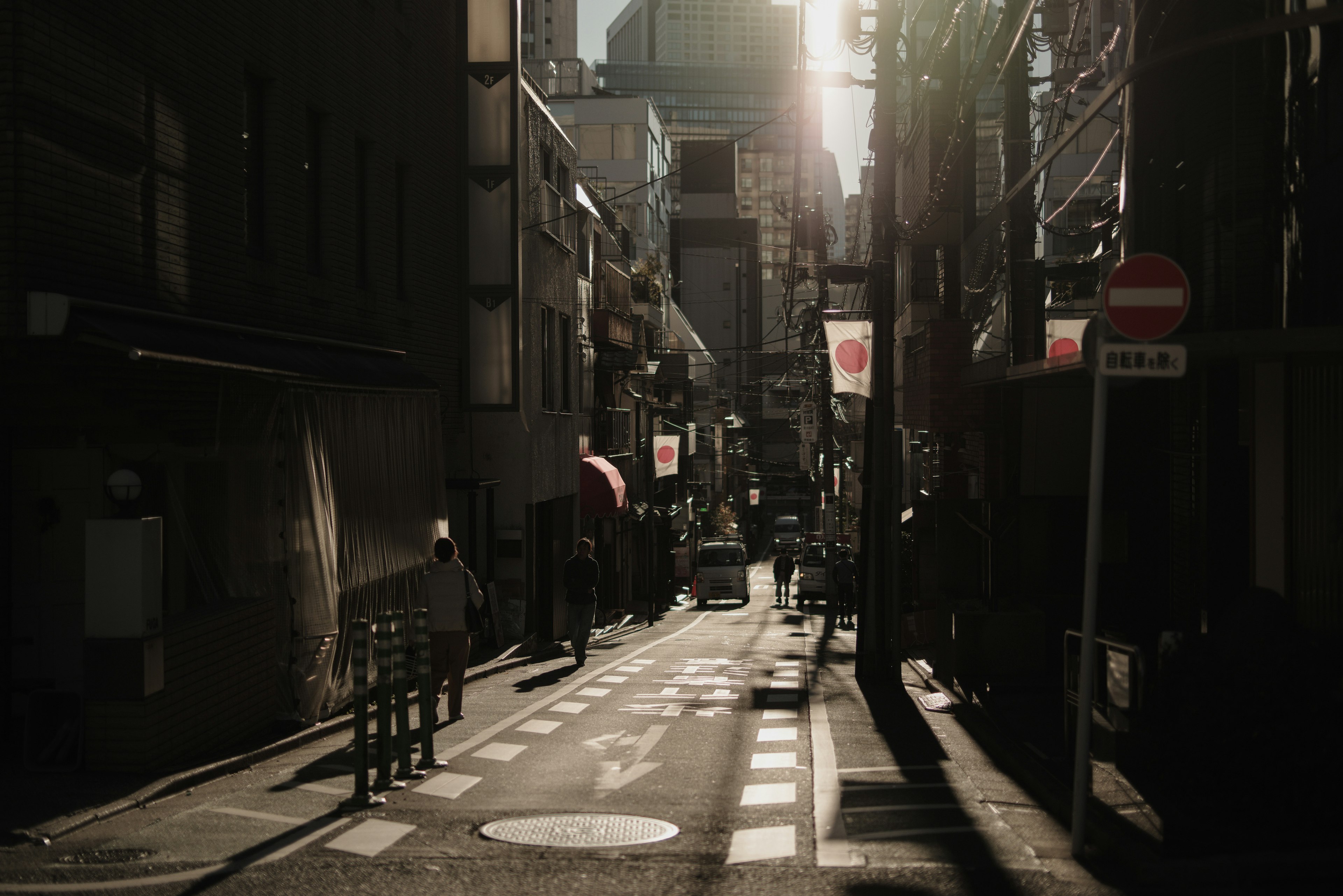 夕暮れ時の東京の狭い通りに人々が歩いている