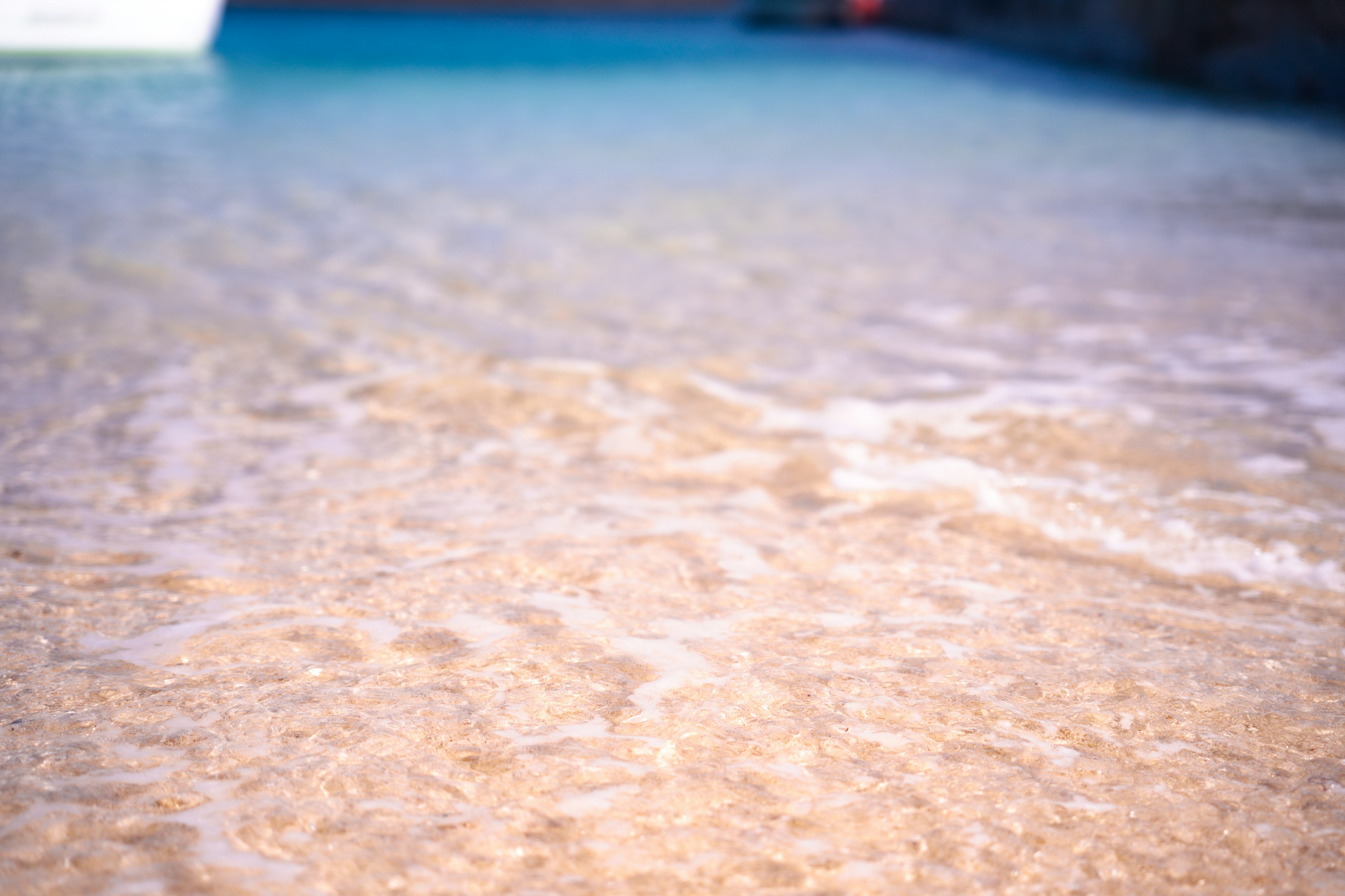 Nahaufnahme von sanften Wellen auf klarem Meerwasser und Sandstrand