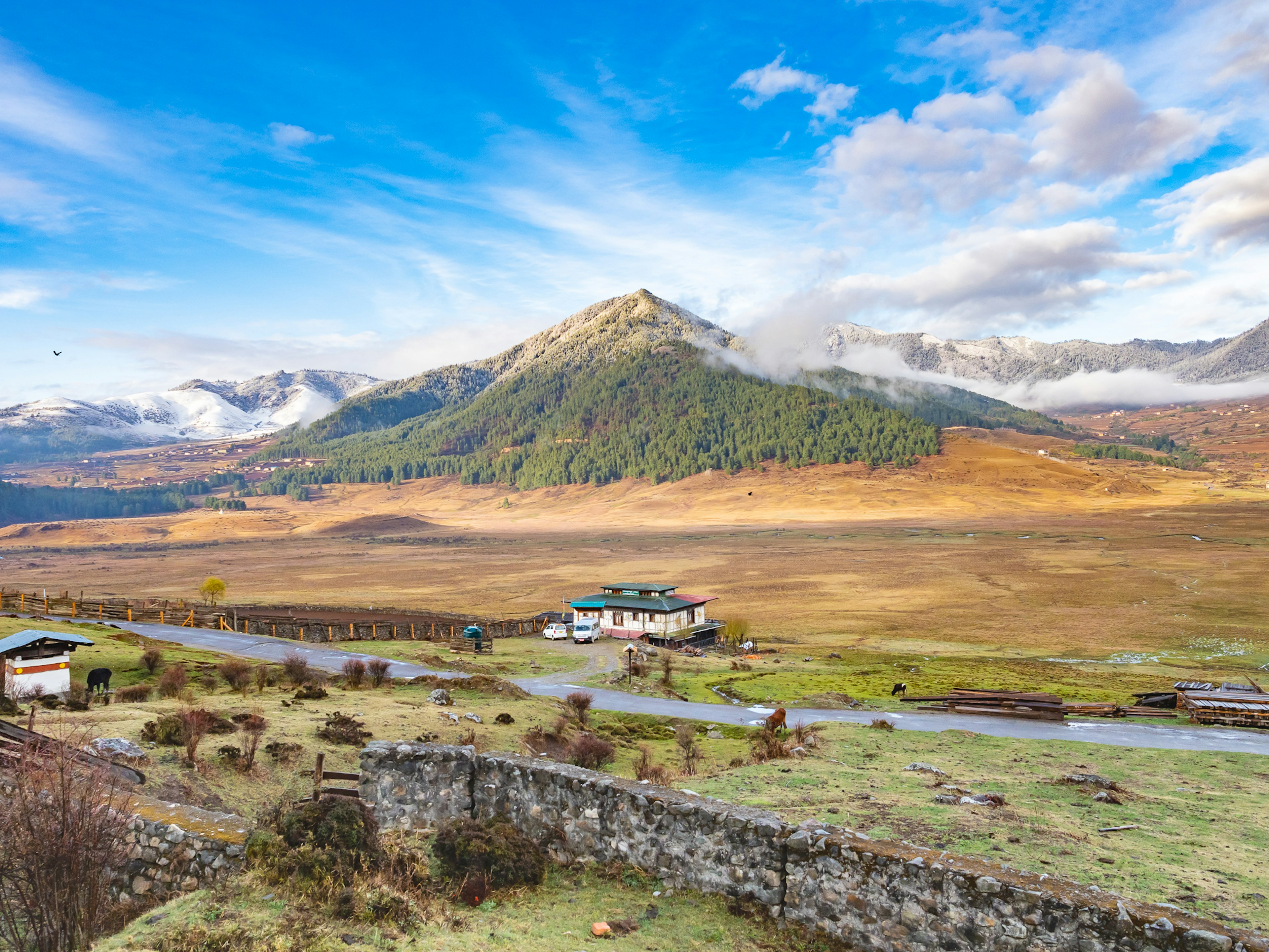 Scenic view of a white house surrounded by mountains and vast grasslands