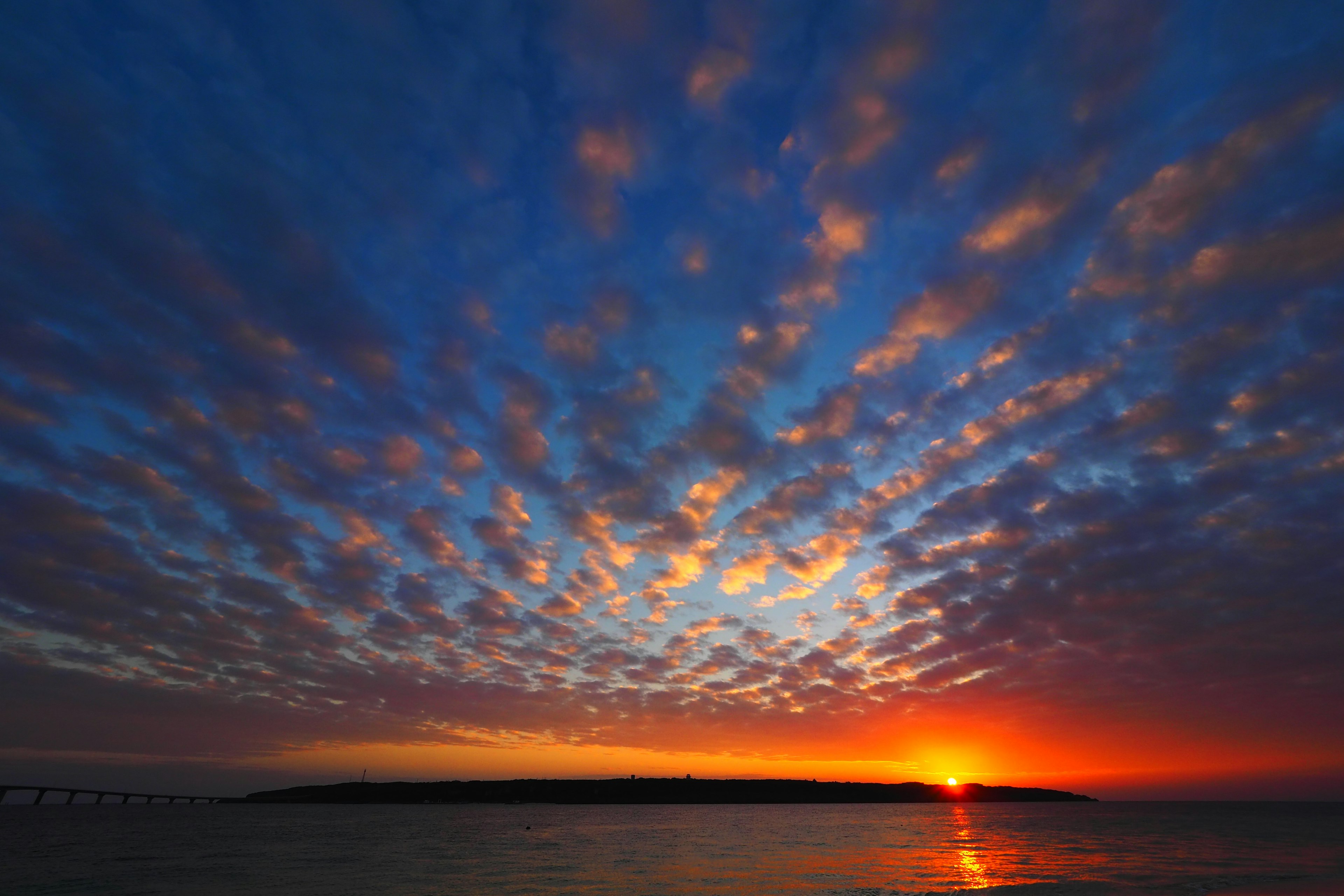 Landschaftsansicht eines Sonnenuntergangs über dem Ozean mit bunten Wolken