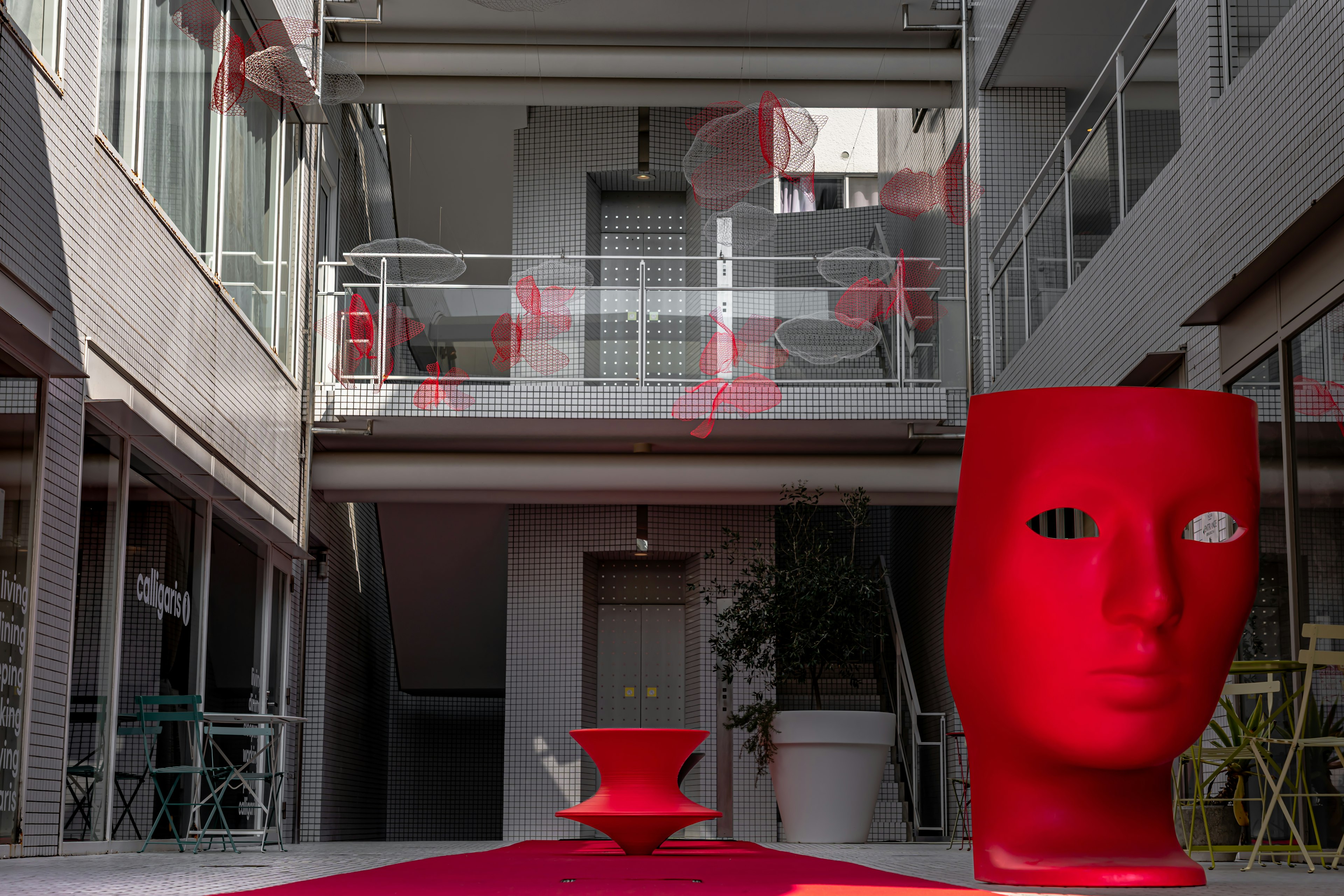 Modern courtyard featuring a red face sculpture and a red flower pot