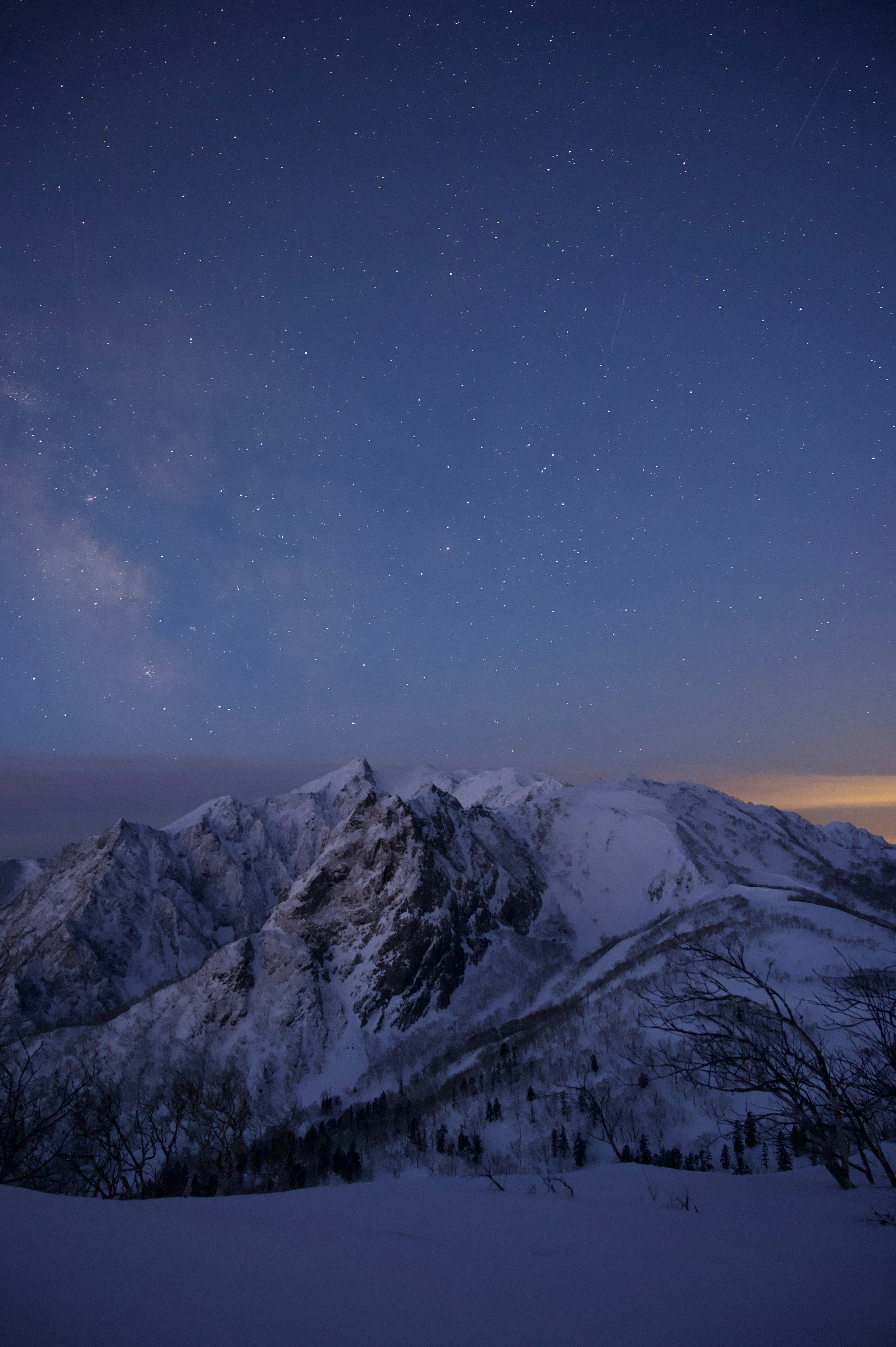 雪に覆われた山々が星空の下に広がる夜の風景