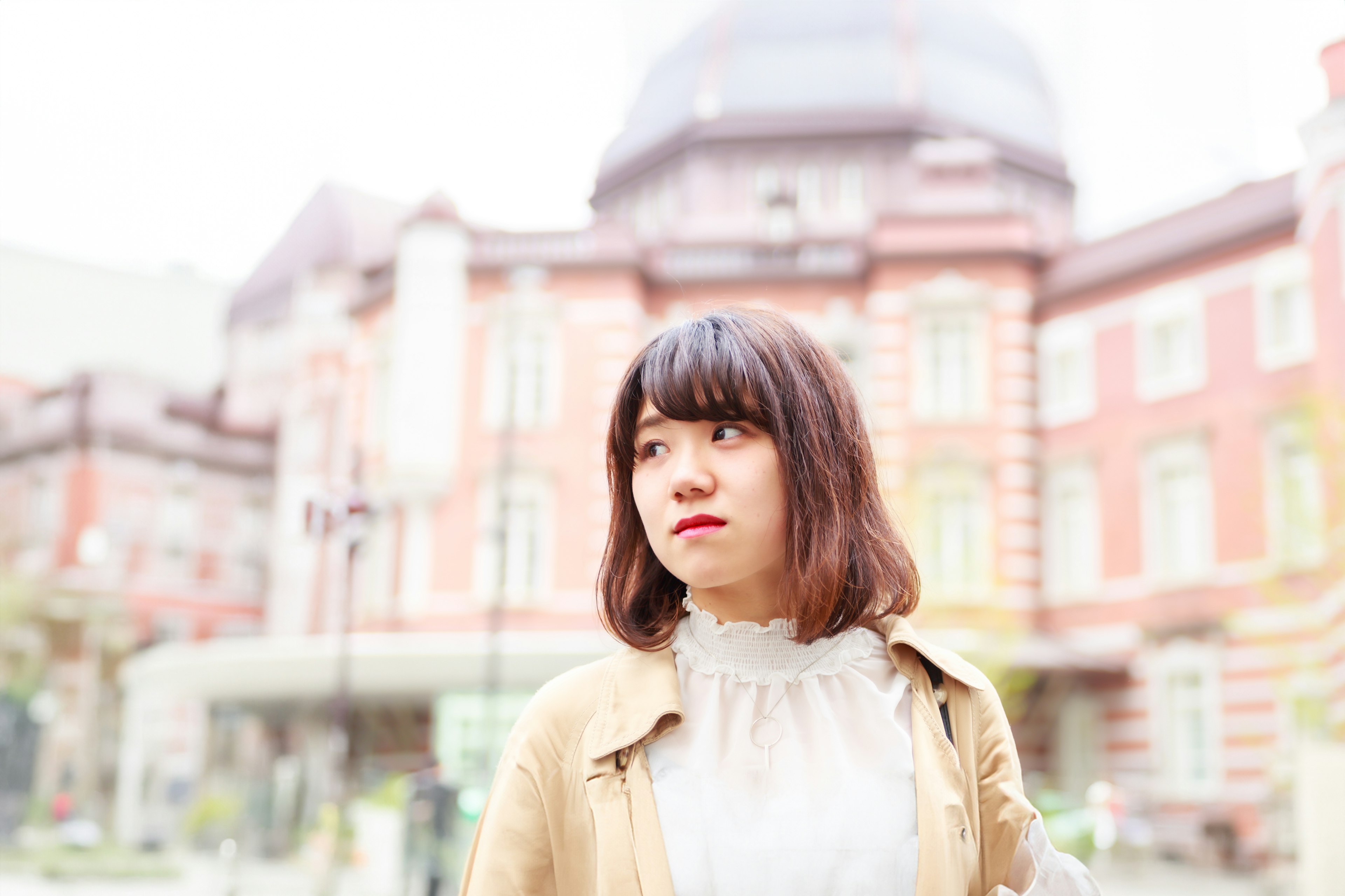 Une femme se tenant devant un bâtiment avec un arrière-plan aux couleurs douces montrant le paysage de Tokyo