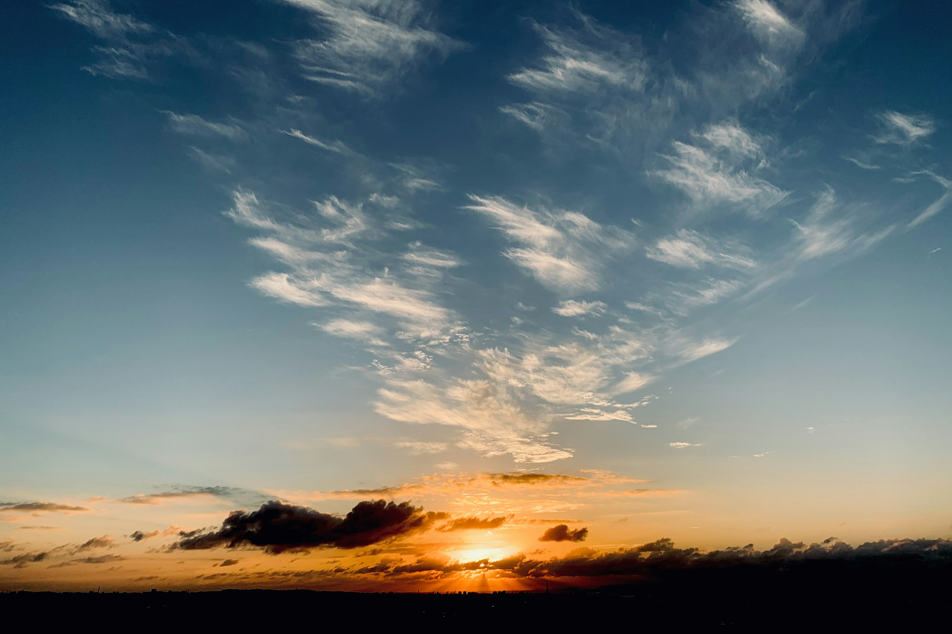 Cielo blu con un vibrante tramonto arancione e nuvole sottili