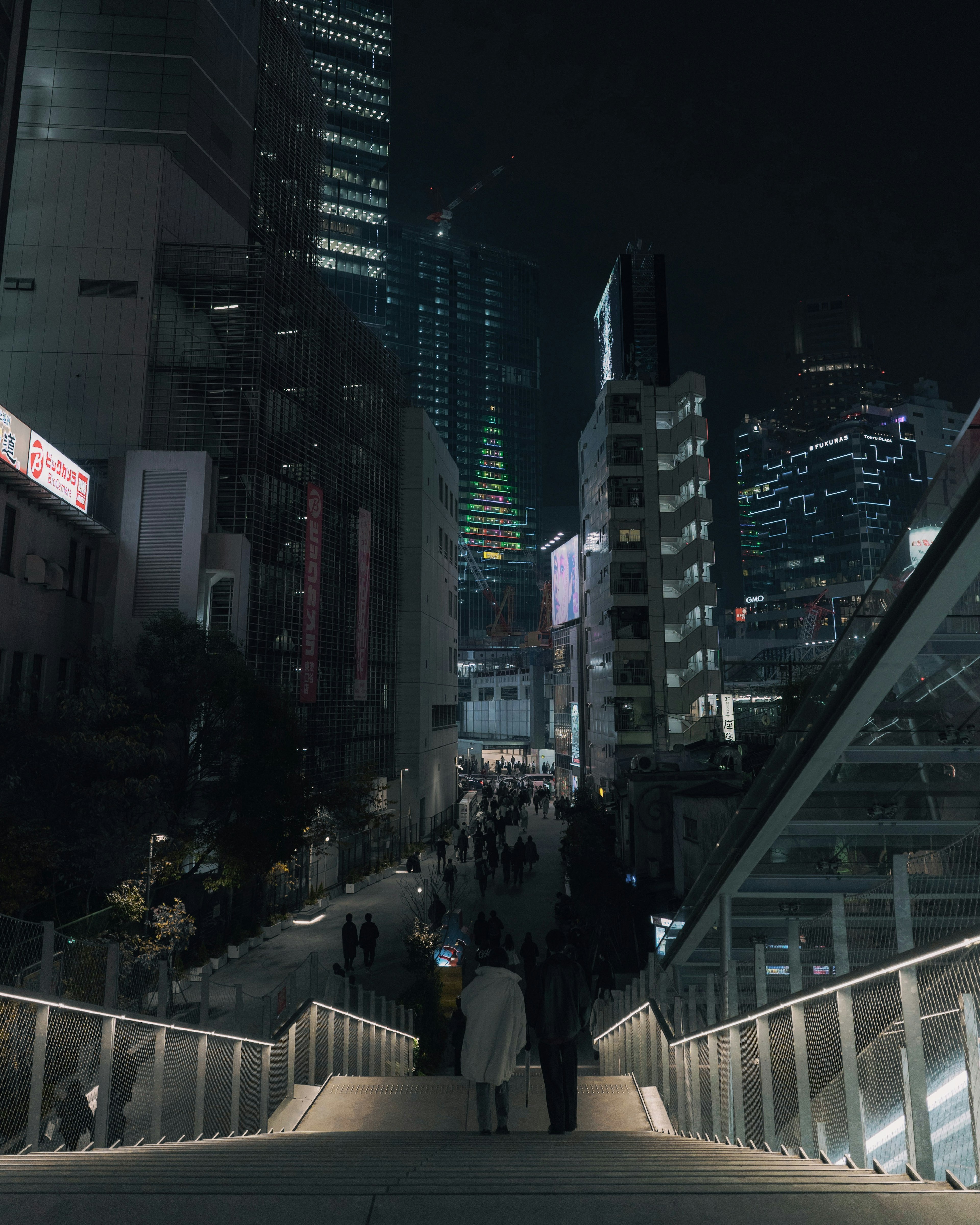 夜の都市景観で人々が集まる階段と高層ビル群を背景にした風景