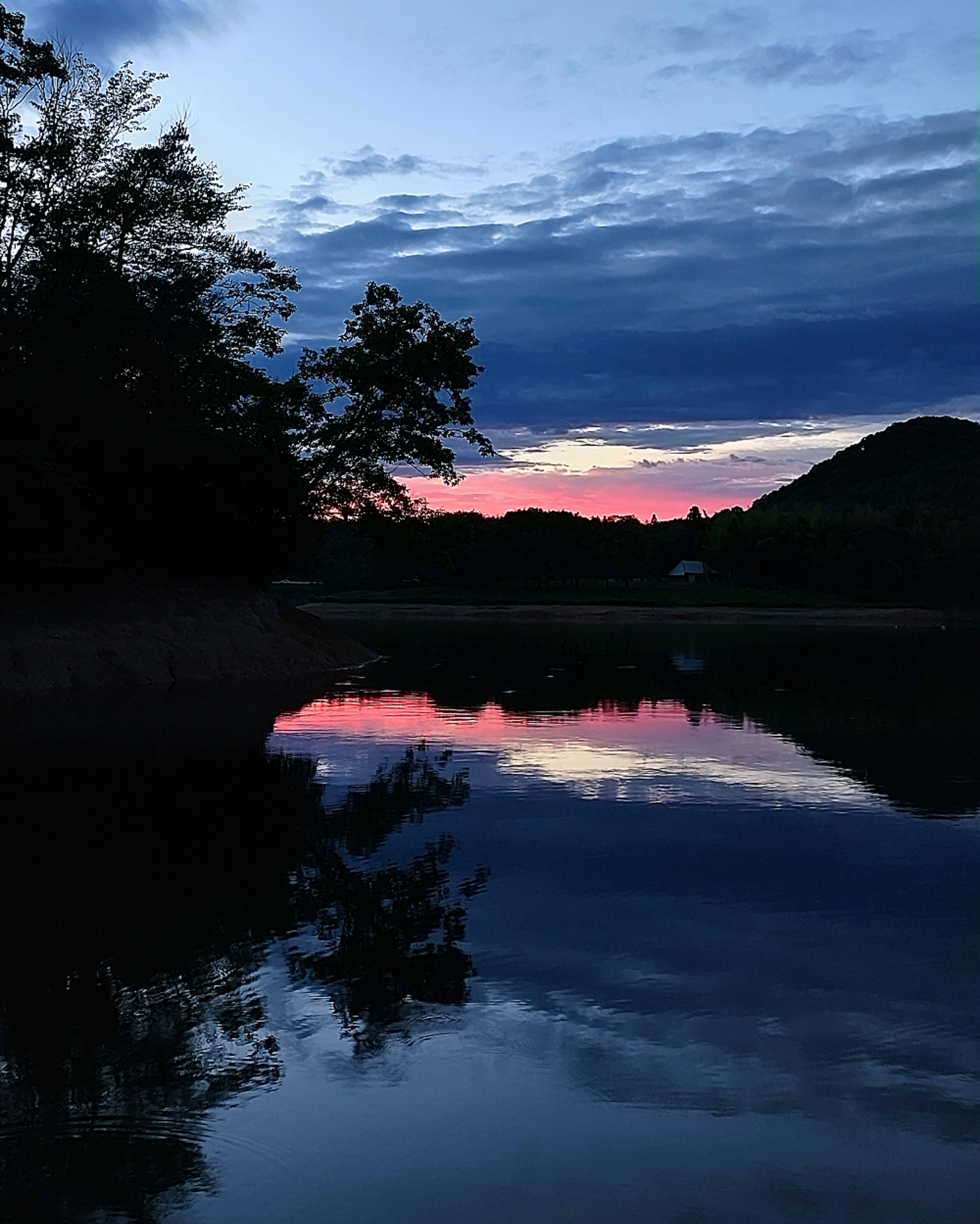 Vista serena junto al lago reflejando hermosos colores del atardecer