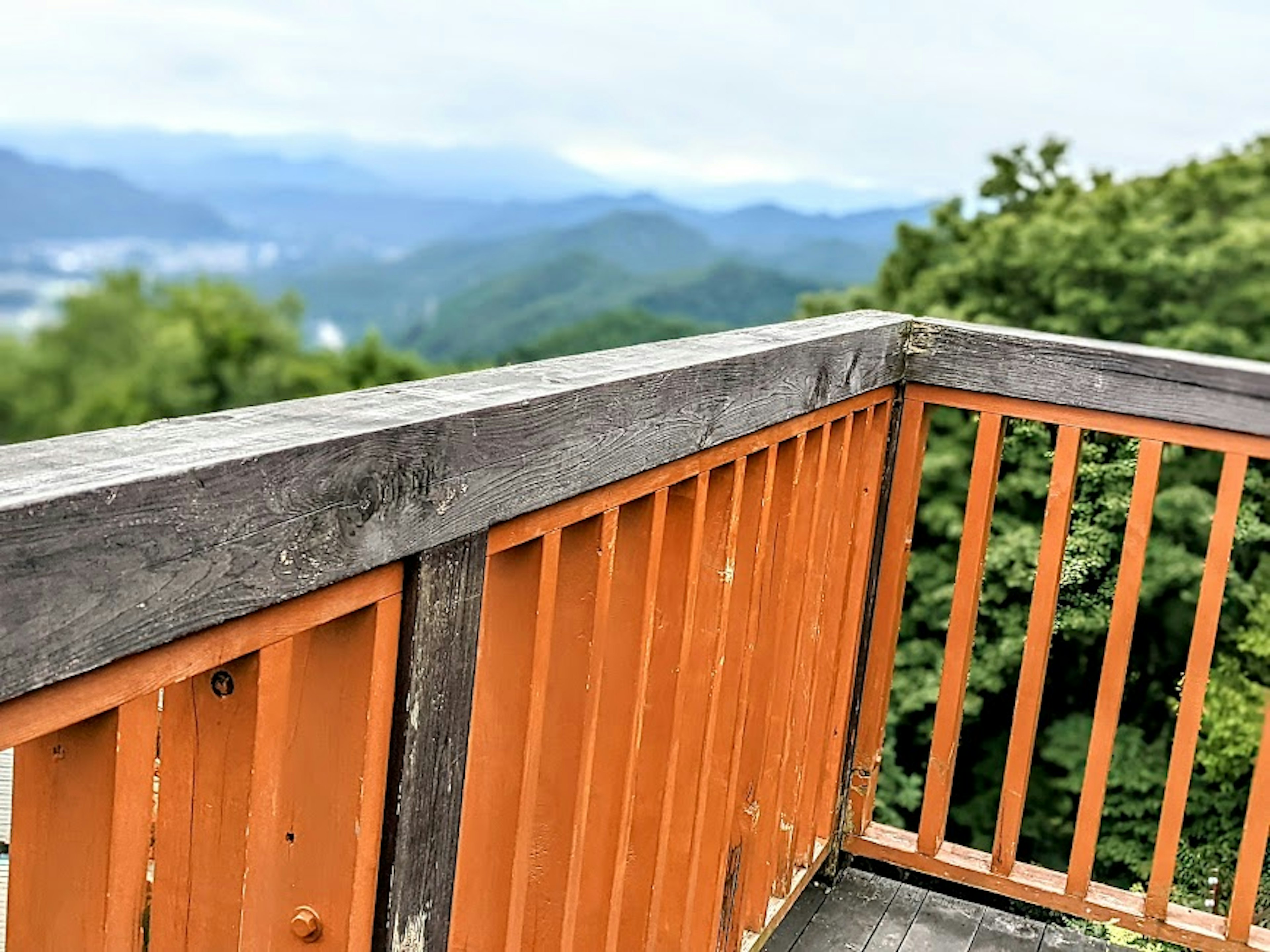 Vista desde un mirador con una barandilla naranja que da a montañas verdes