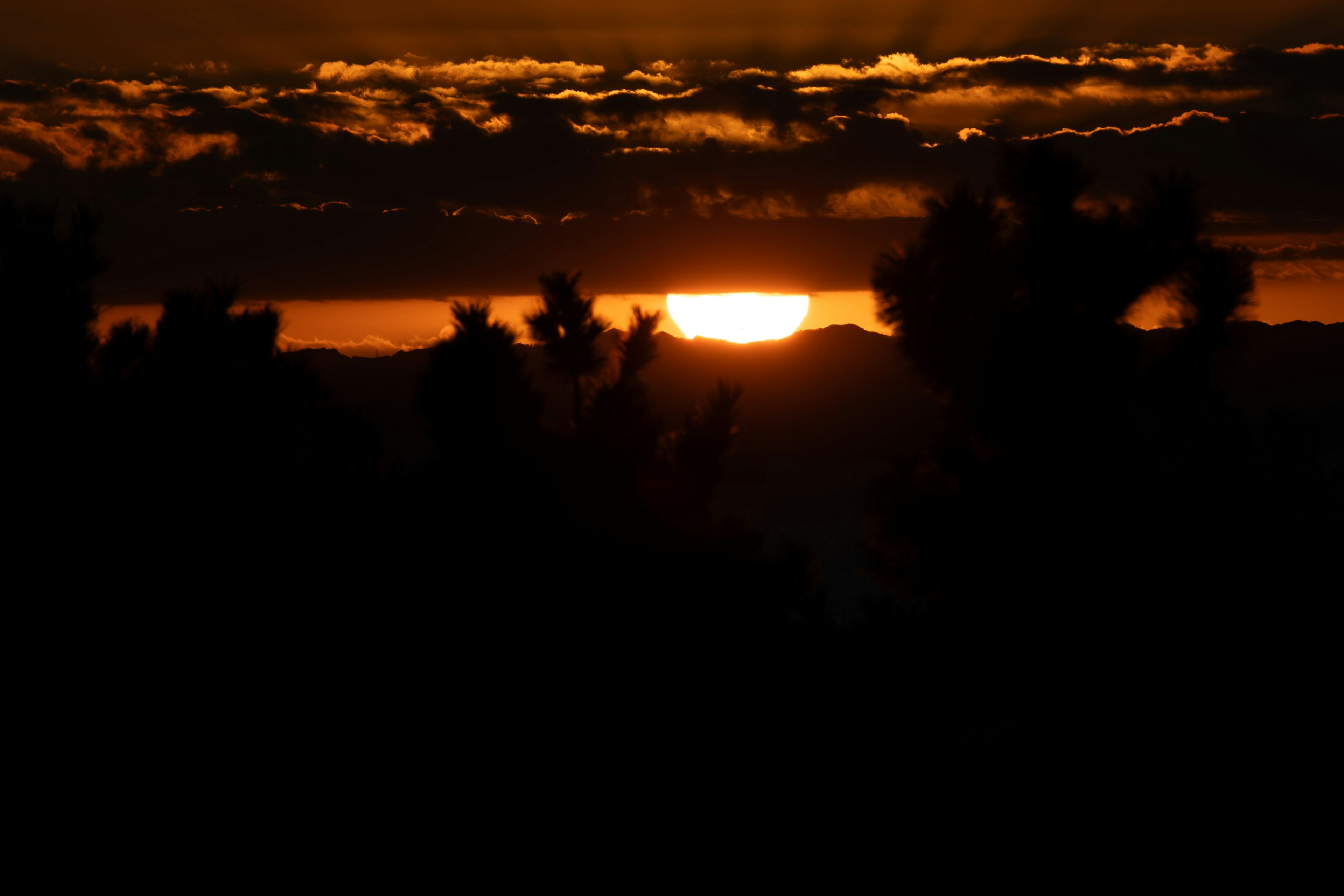 夕日が雲の間から見えるシルエットの風景