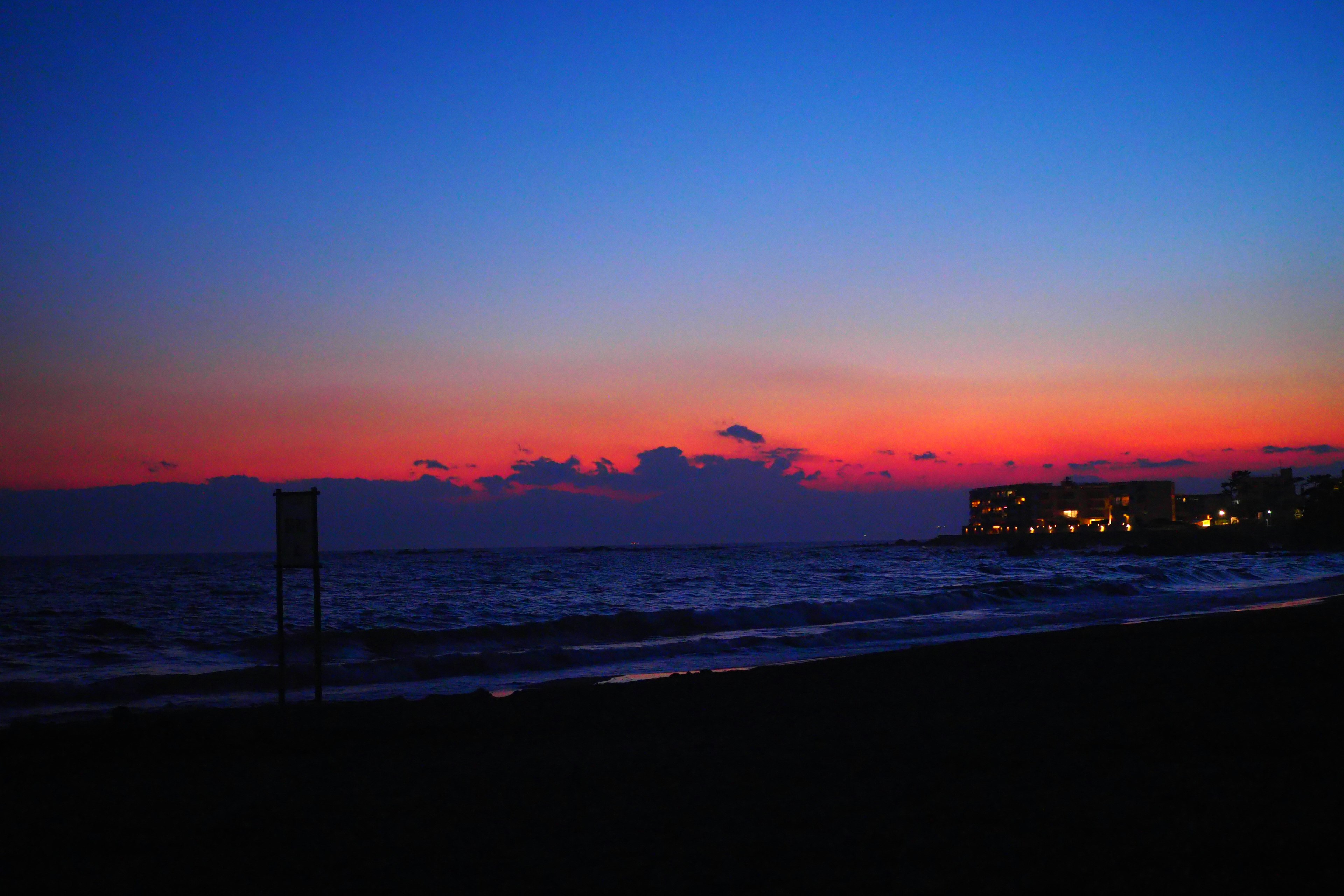 Beach scene with blue sky and orange sunset reflecting on the sea