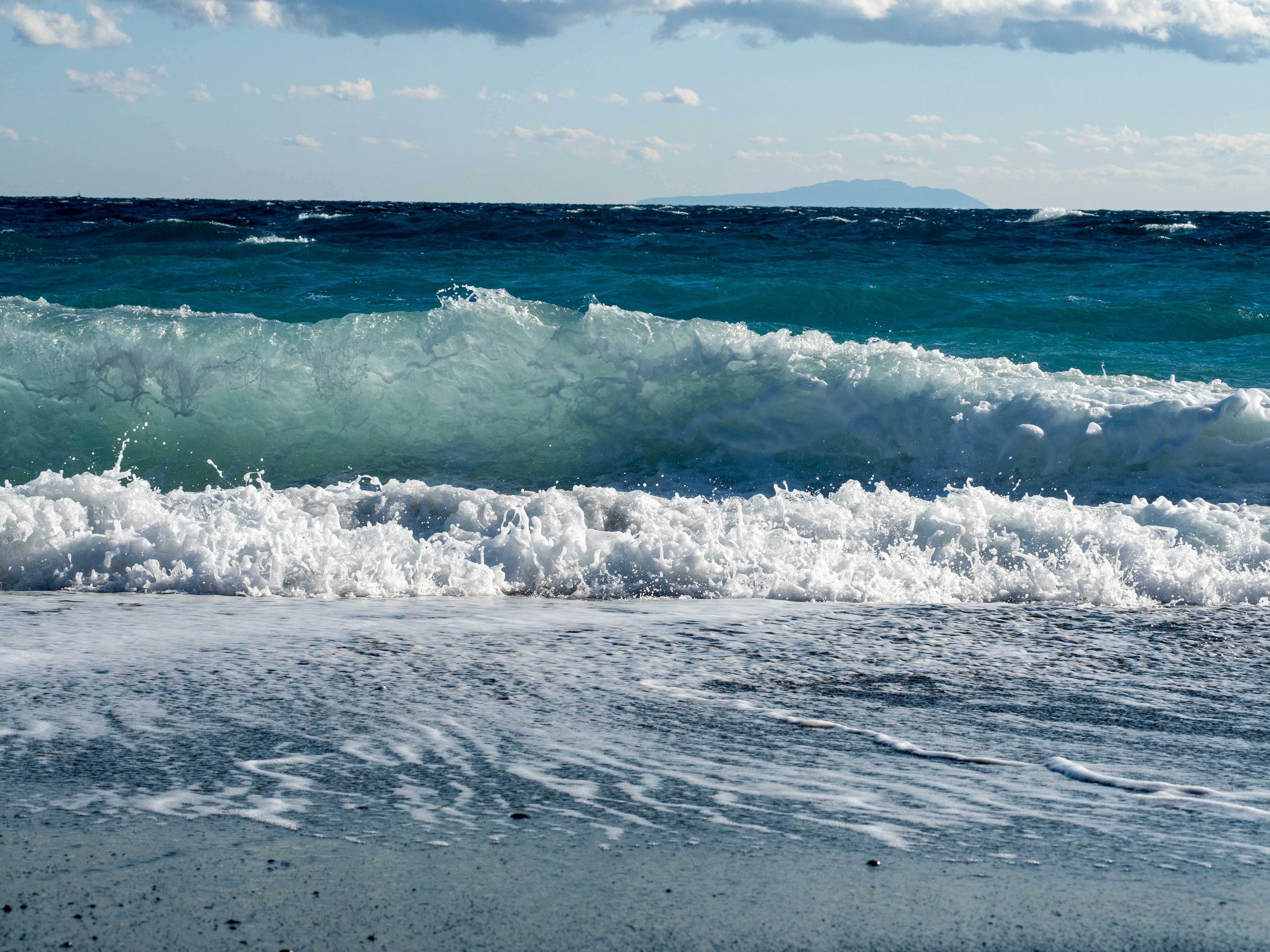 Gelombang laut biru menghantam pantai