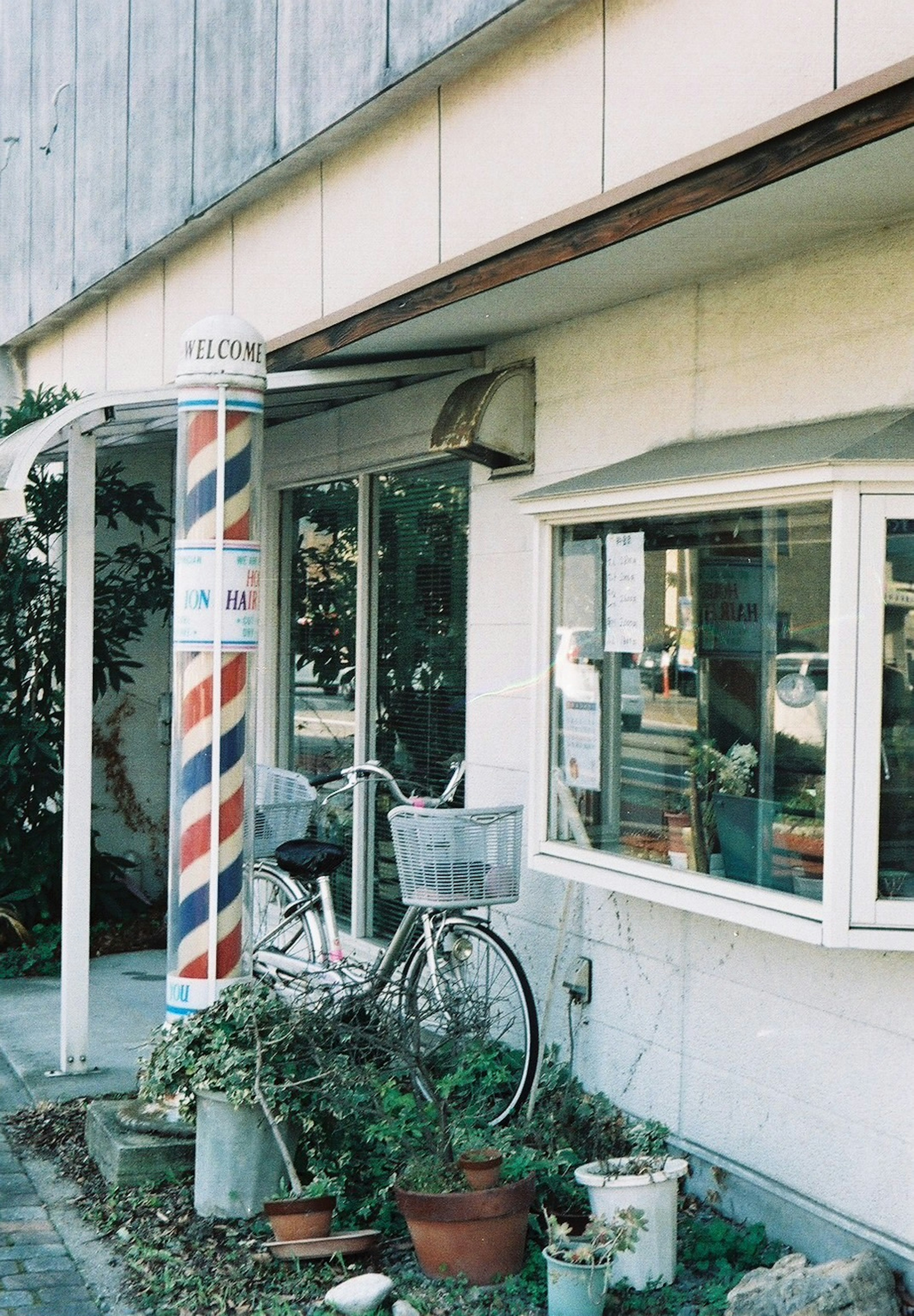 Exterior de una barbería con una bicicleta y un poste decorativo