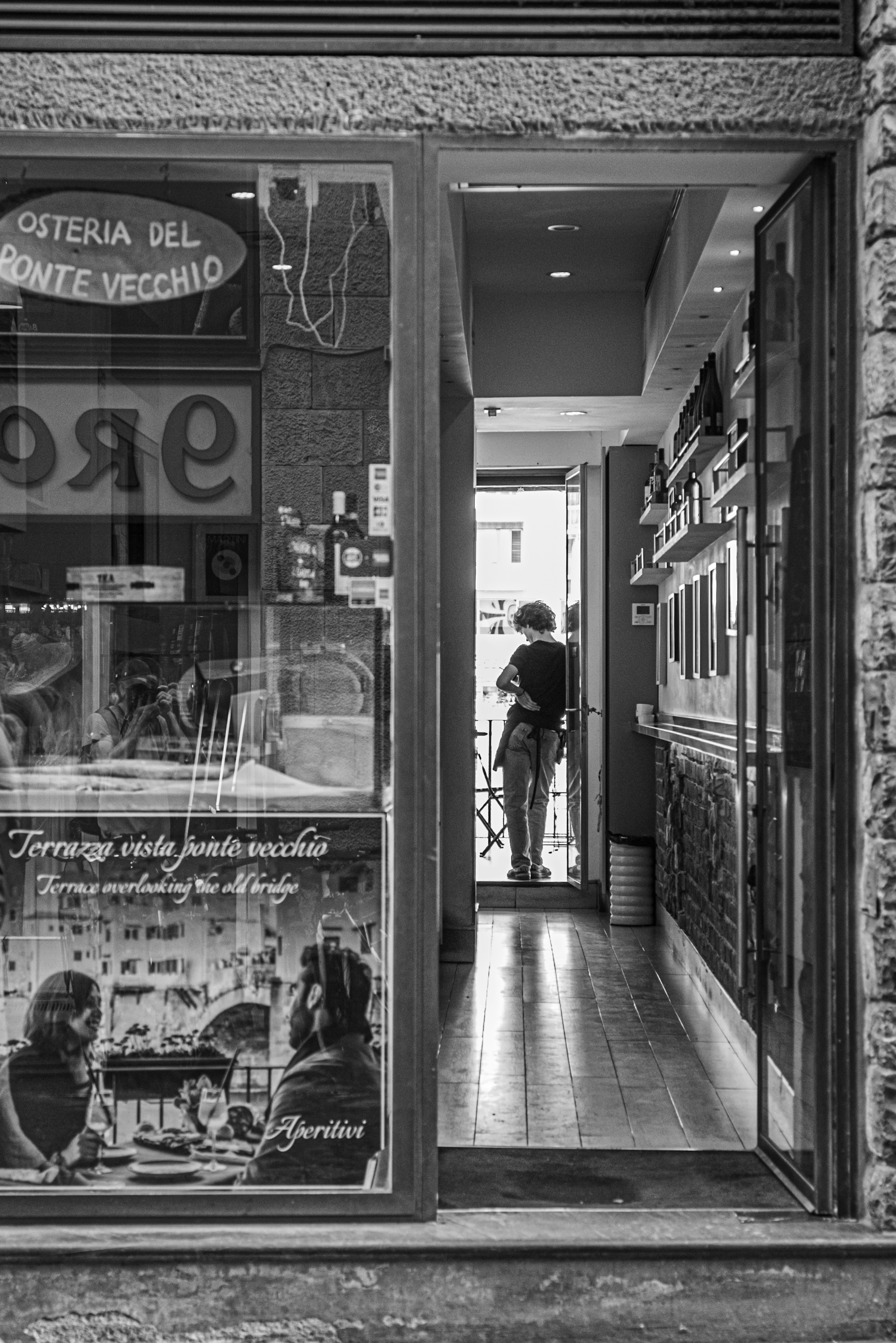 A woman standing at the entrance of a bistro Black and white photo showing interior decor and menu