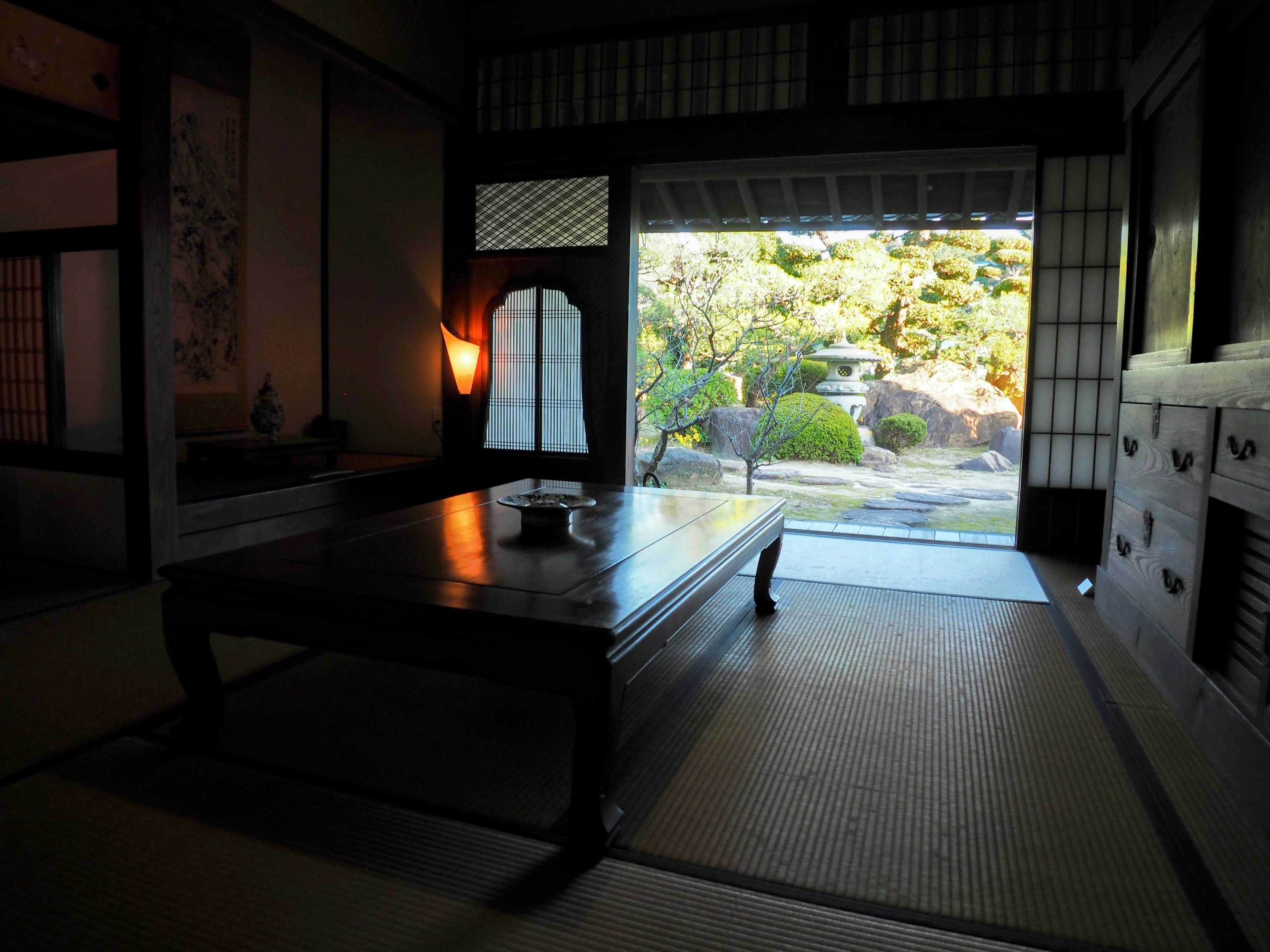 Vista interna di una stanza giapponese che si affaccia su un giardino Tavolo basso su pavimento tatami Illuminazione soffusa crea un'atmosfera calda