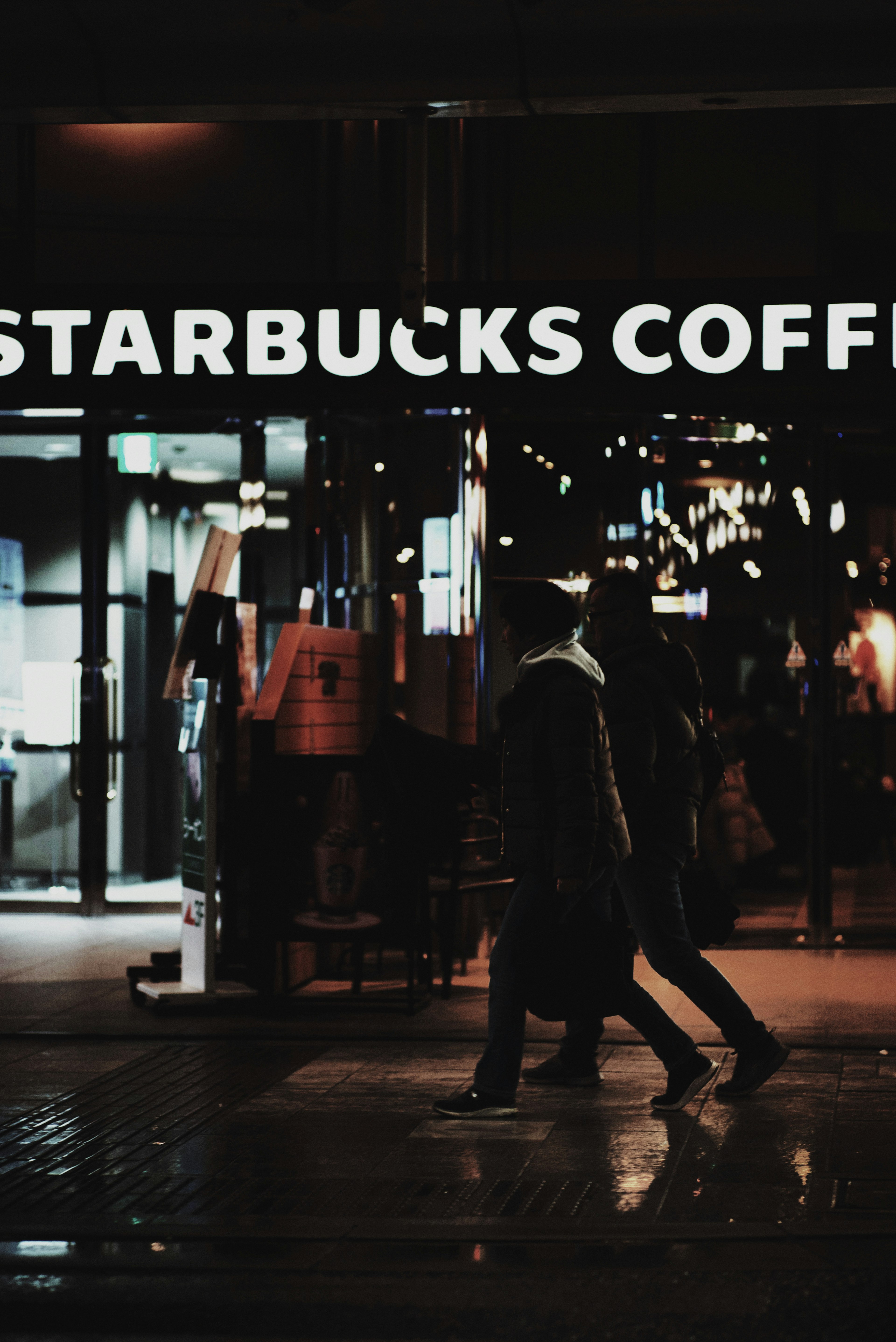 Fachada de Starbucks con siluetas de peatones