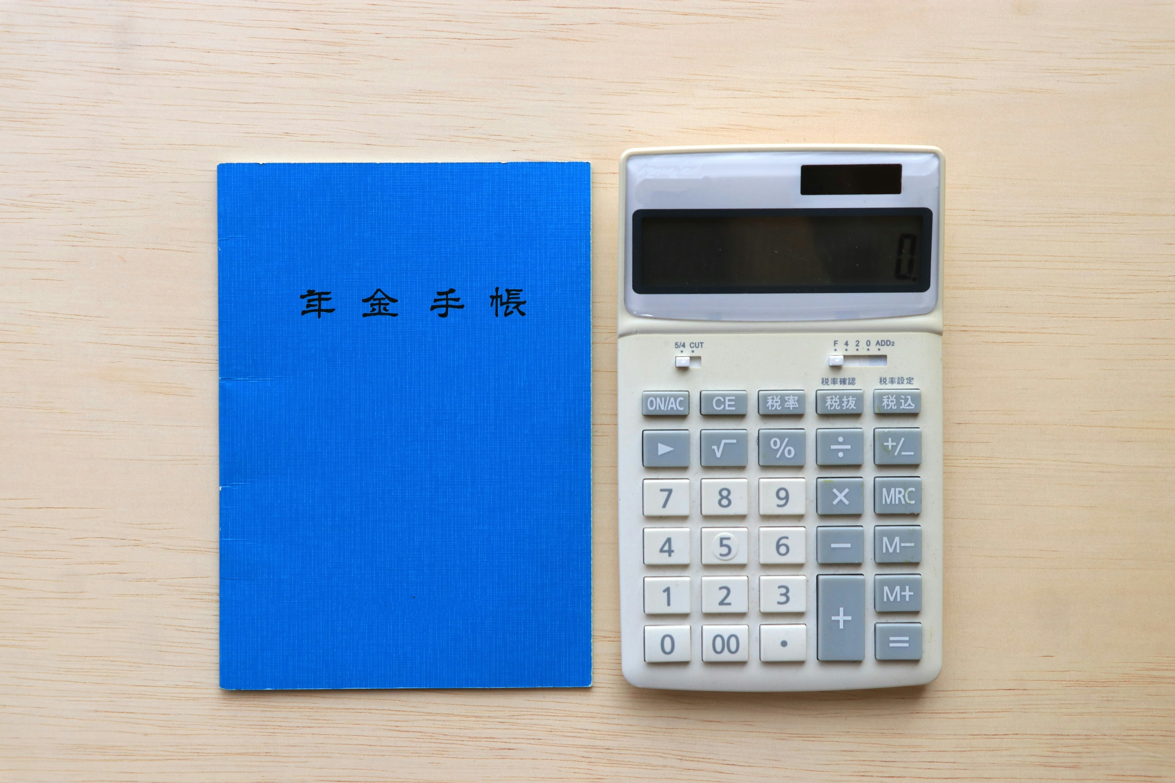 A blue notebook and a calculator placed on a wooden table