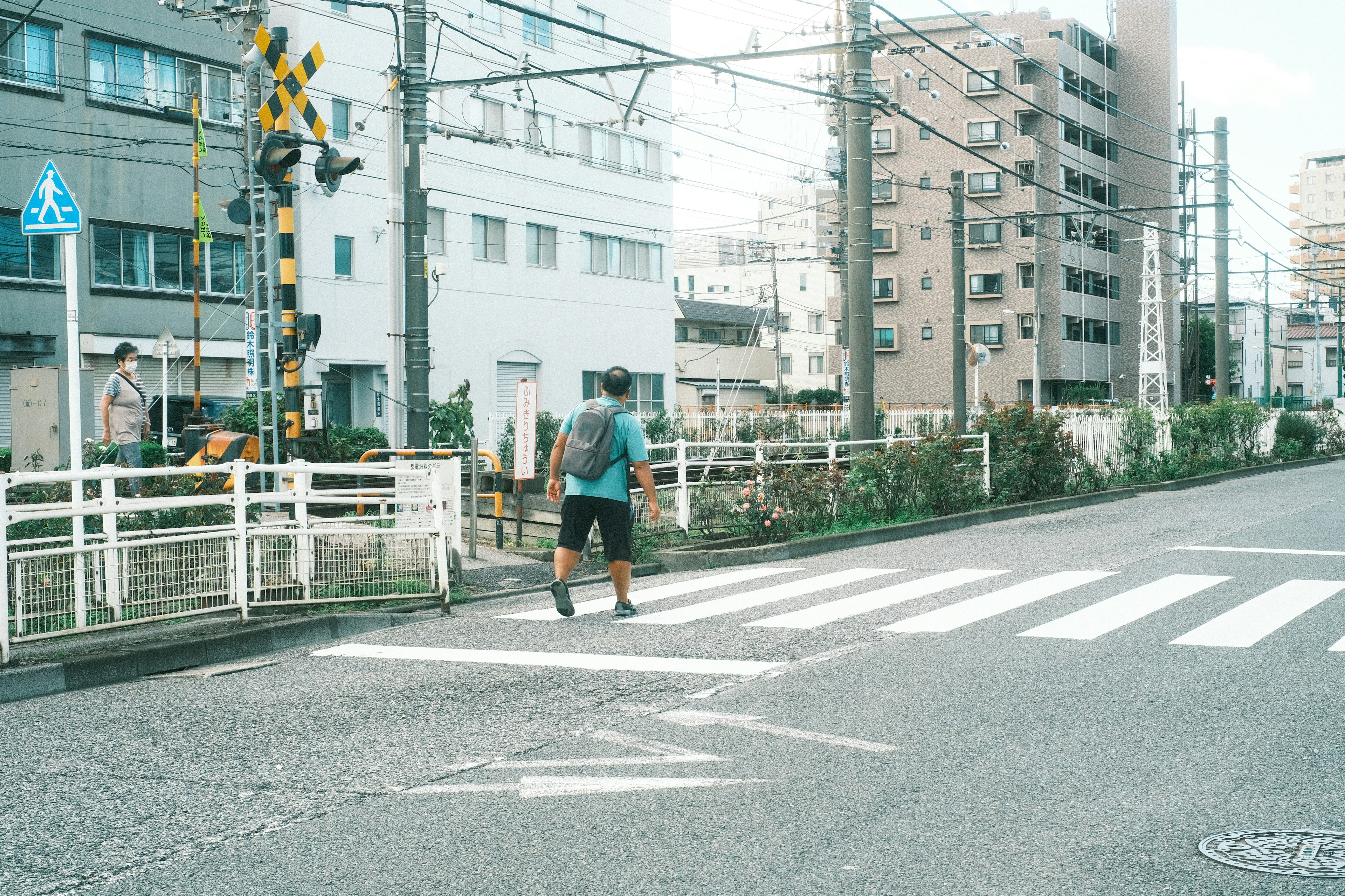 一個人在城市的斑馬線上過馬路，周圍有建築