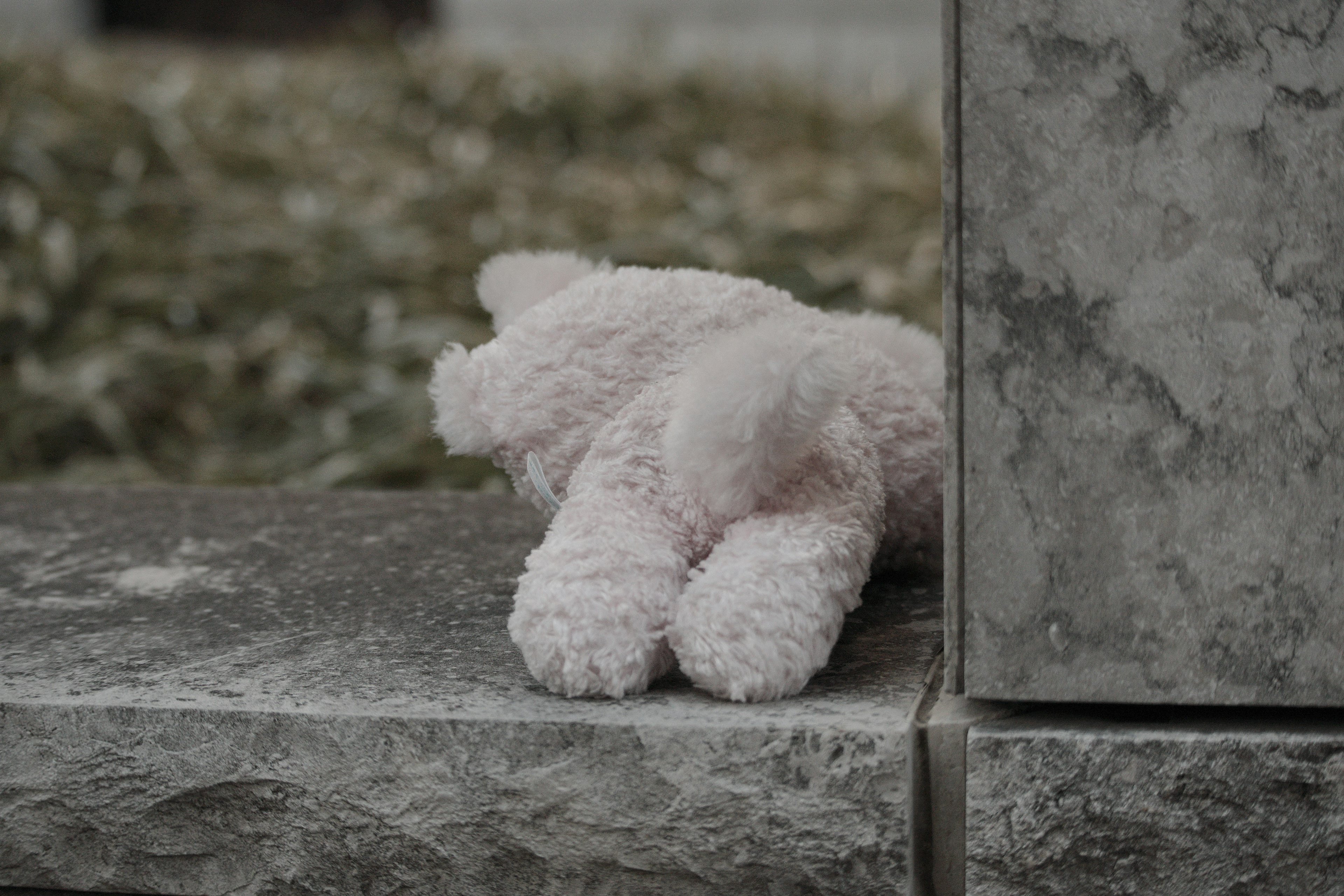 Un animal en peluche rose doux reposant sur une surface en pierre