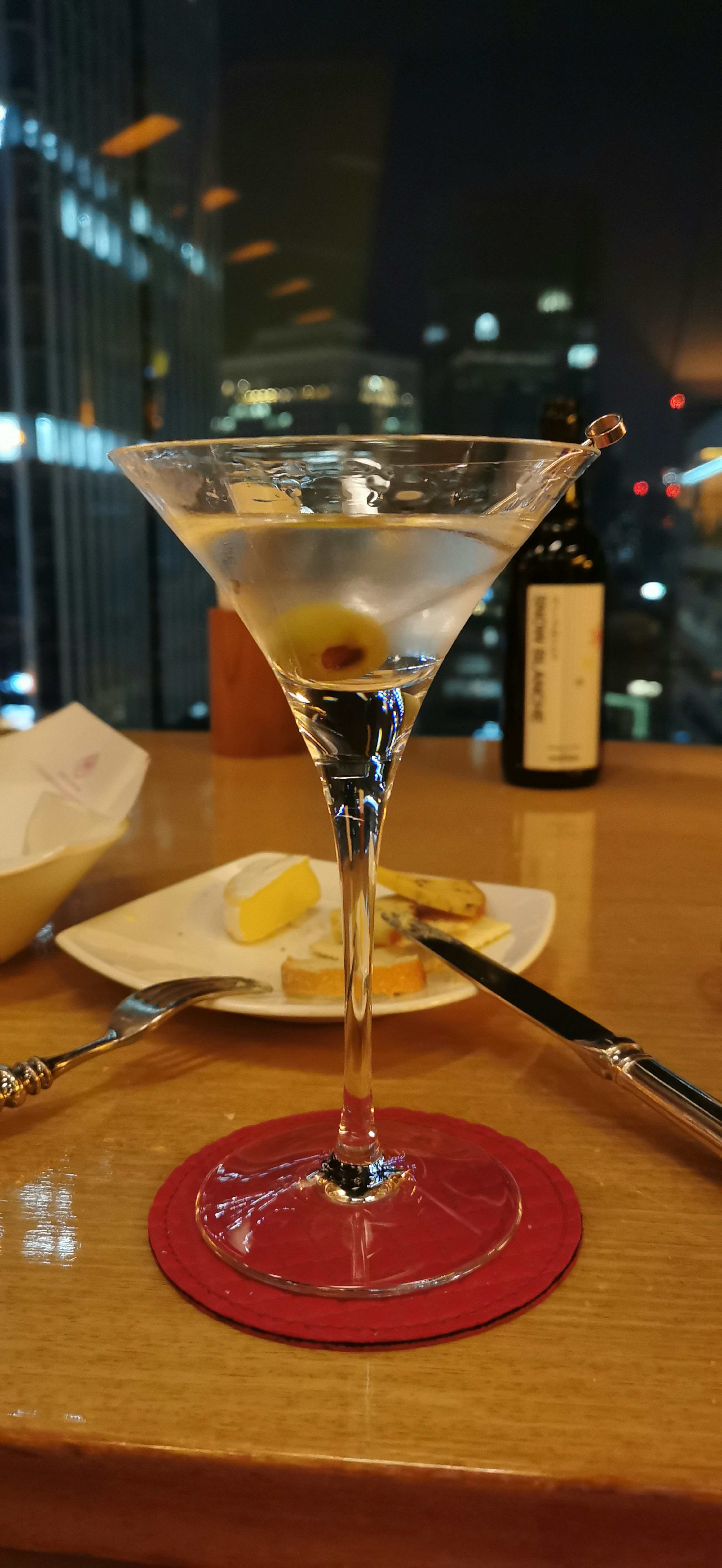 Gelas martini dengan pemandangan kota di malam hari