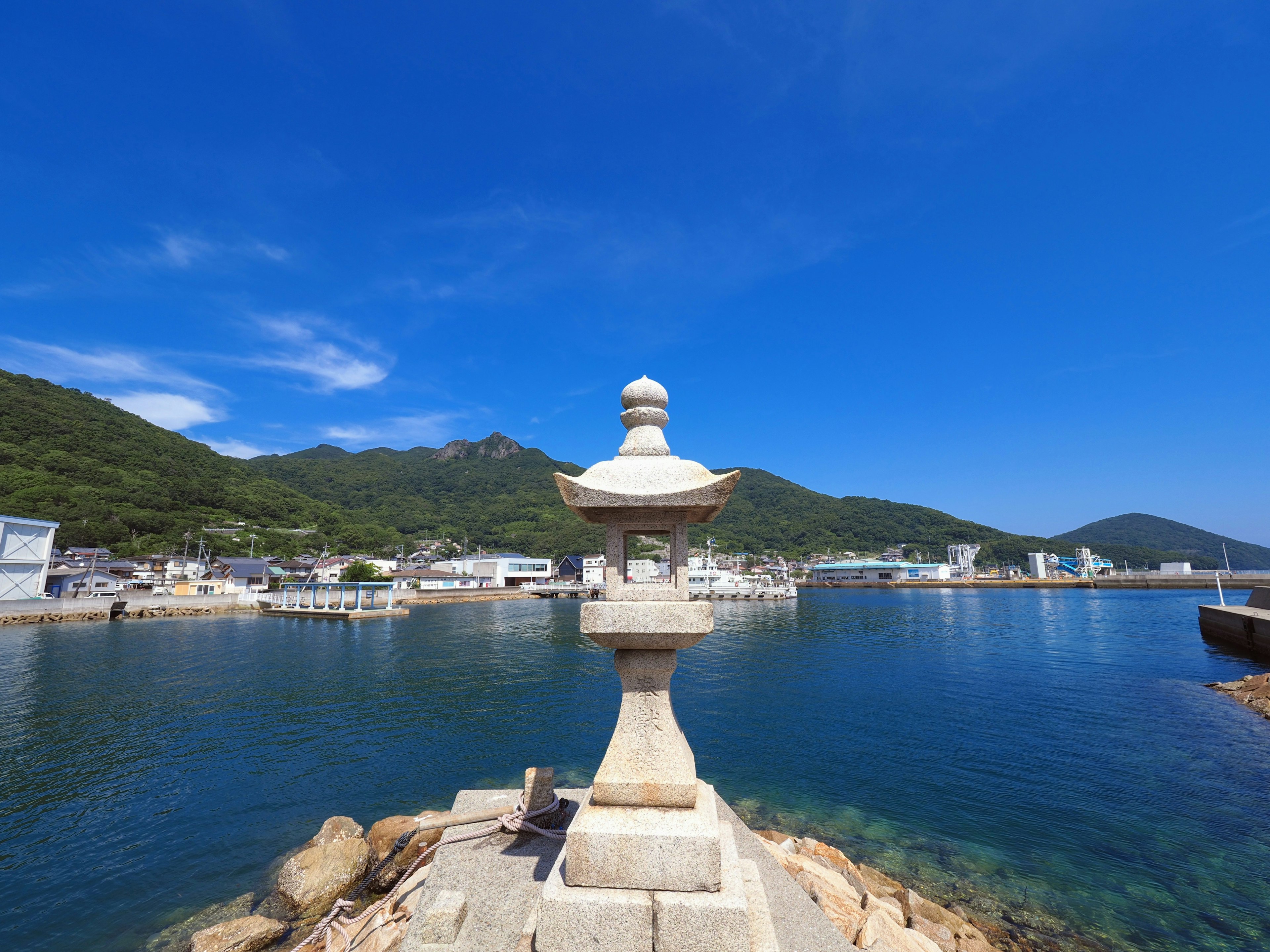 Stone lantern by the water with a clear blue sky harbor town view