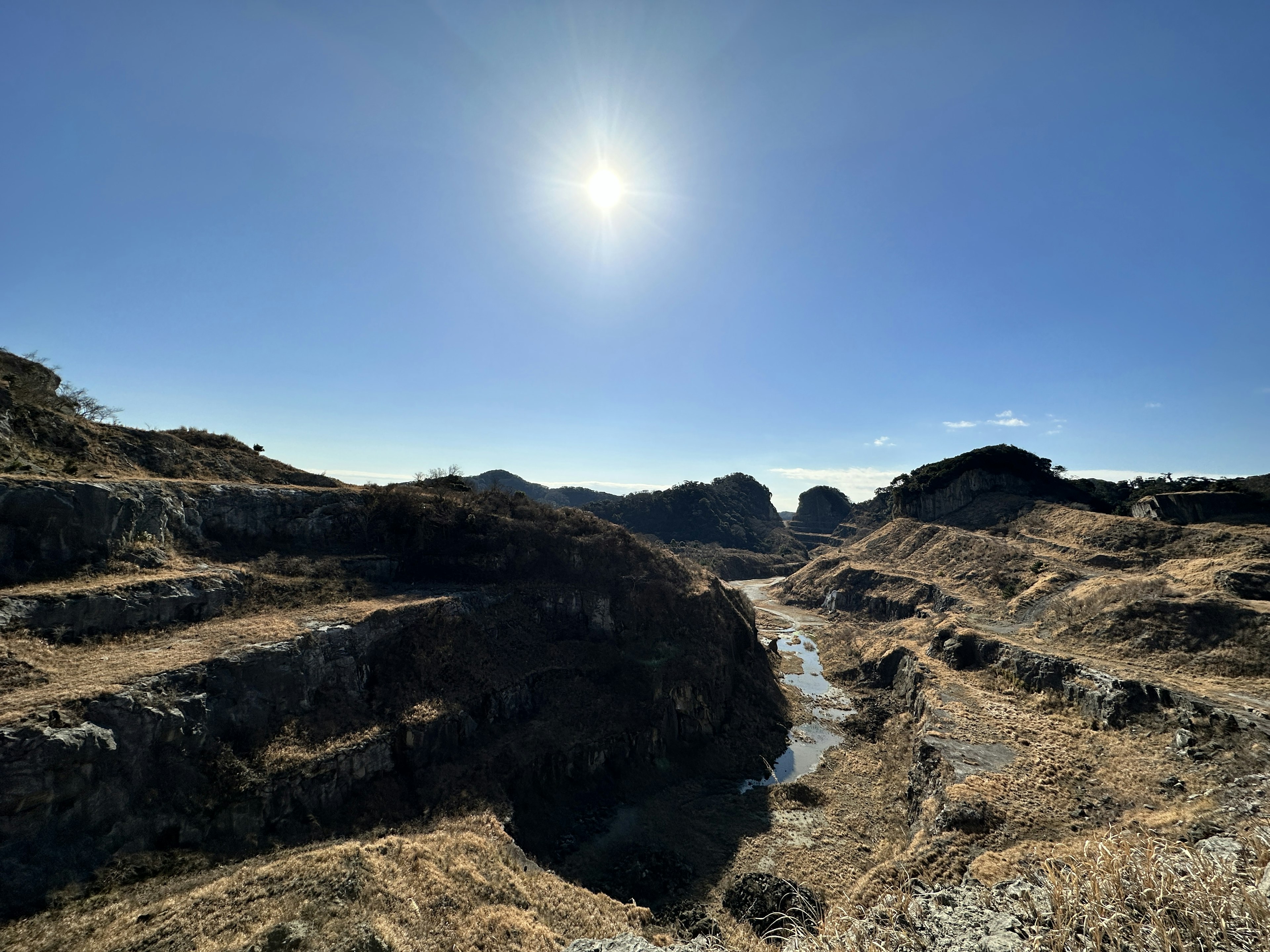 Dry canyon landscape with rocky formations under bright sunlight