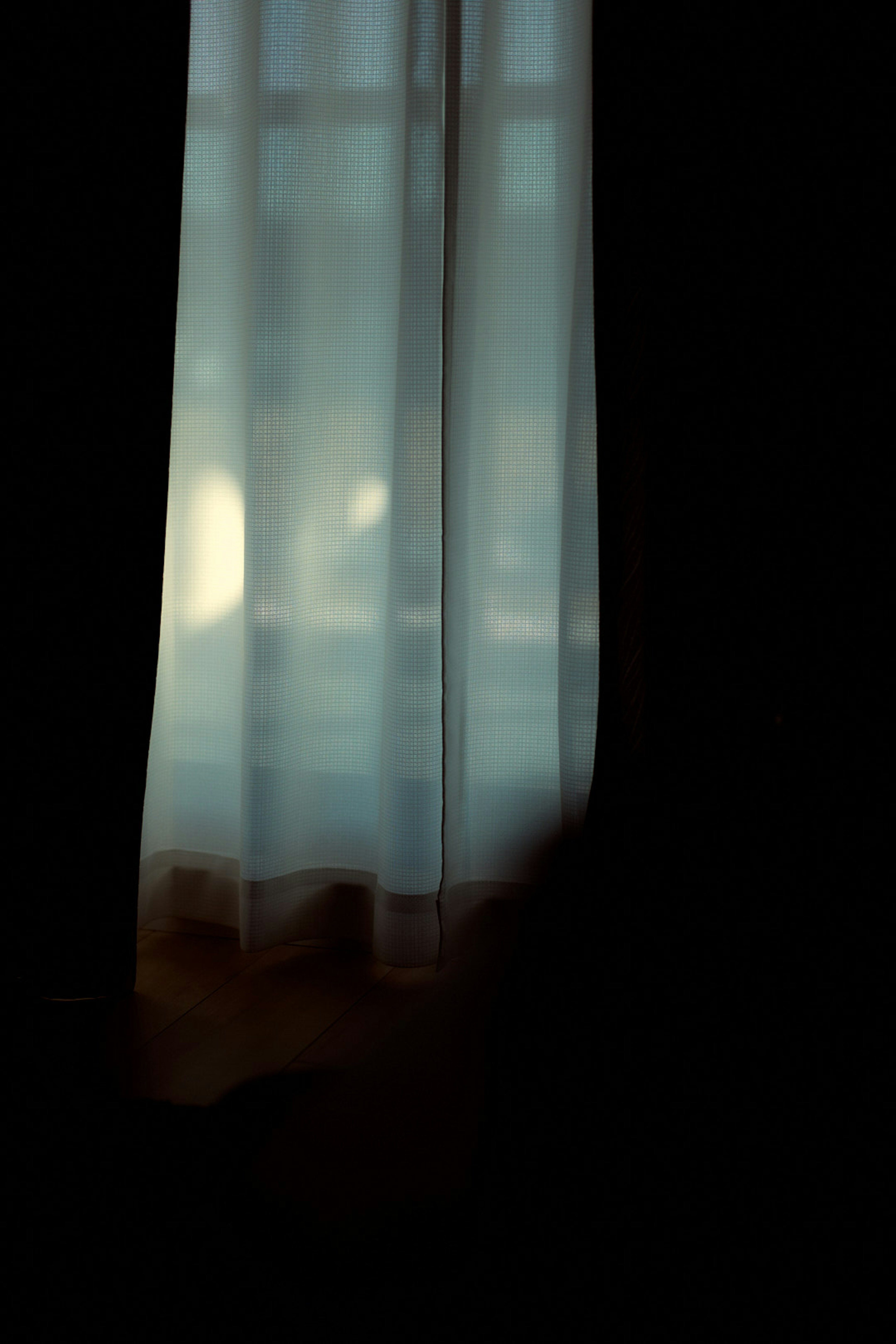 Soft light filtering through a sheer curtain in a quiet room