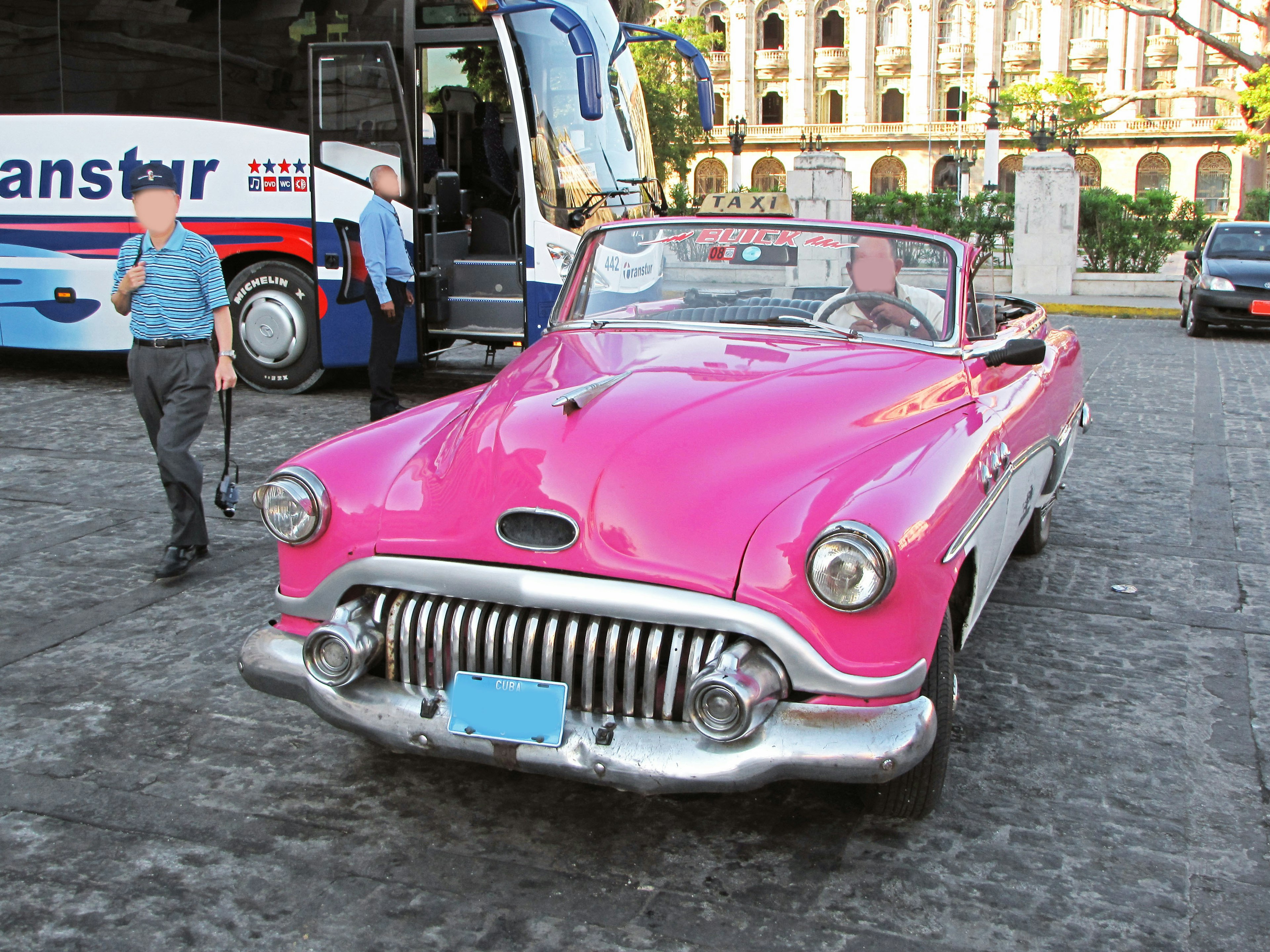 Sebuah mobil convertible pink cerah diparkir di jalan