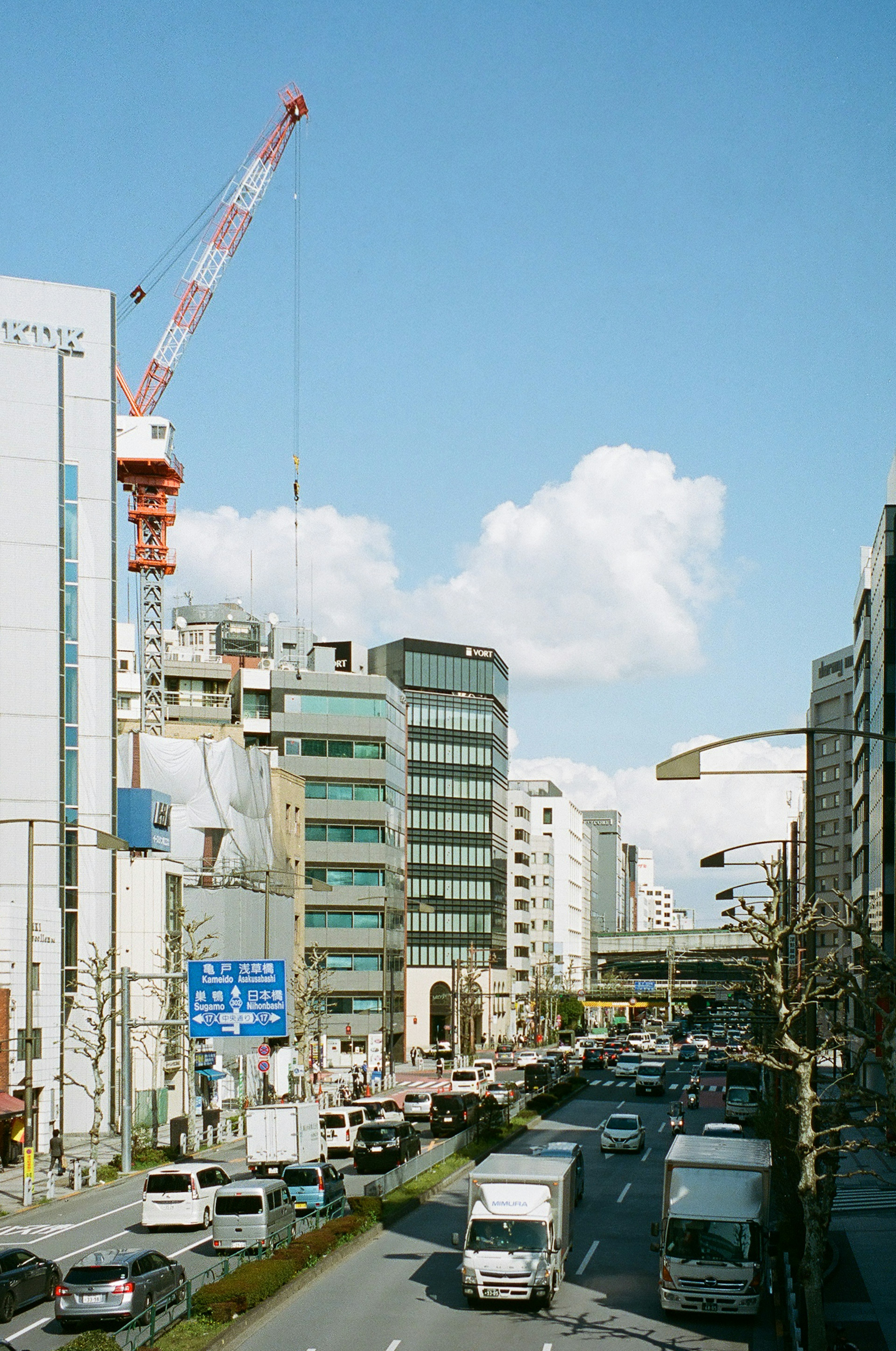 都市の風景に見える建設クレーンと交通の流れ