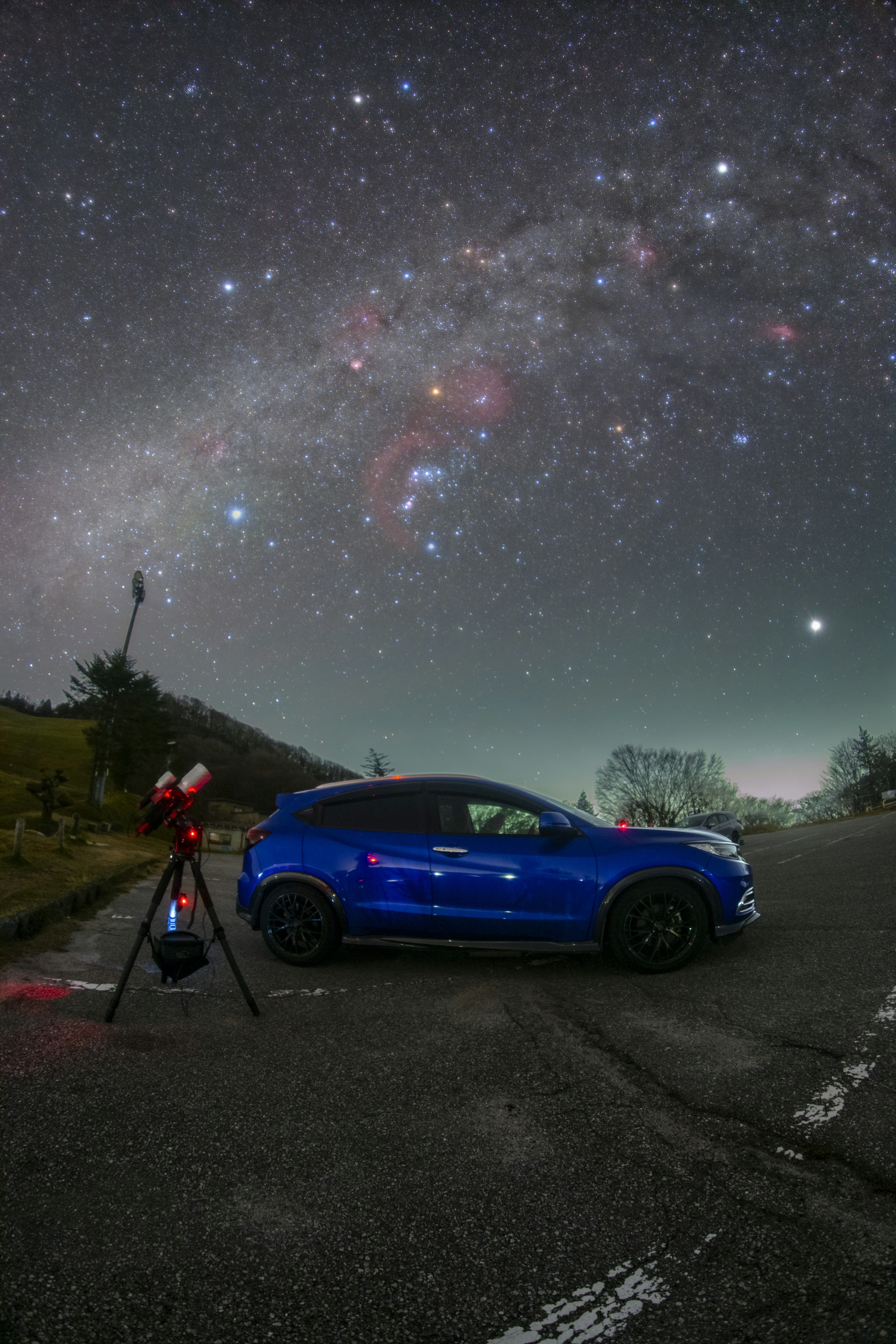 青い車と星空の風景で三脚が立てられている