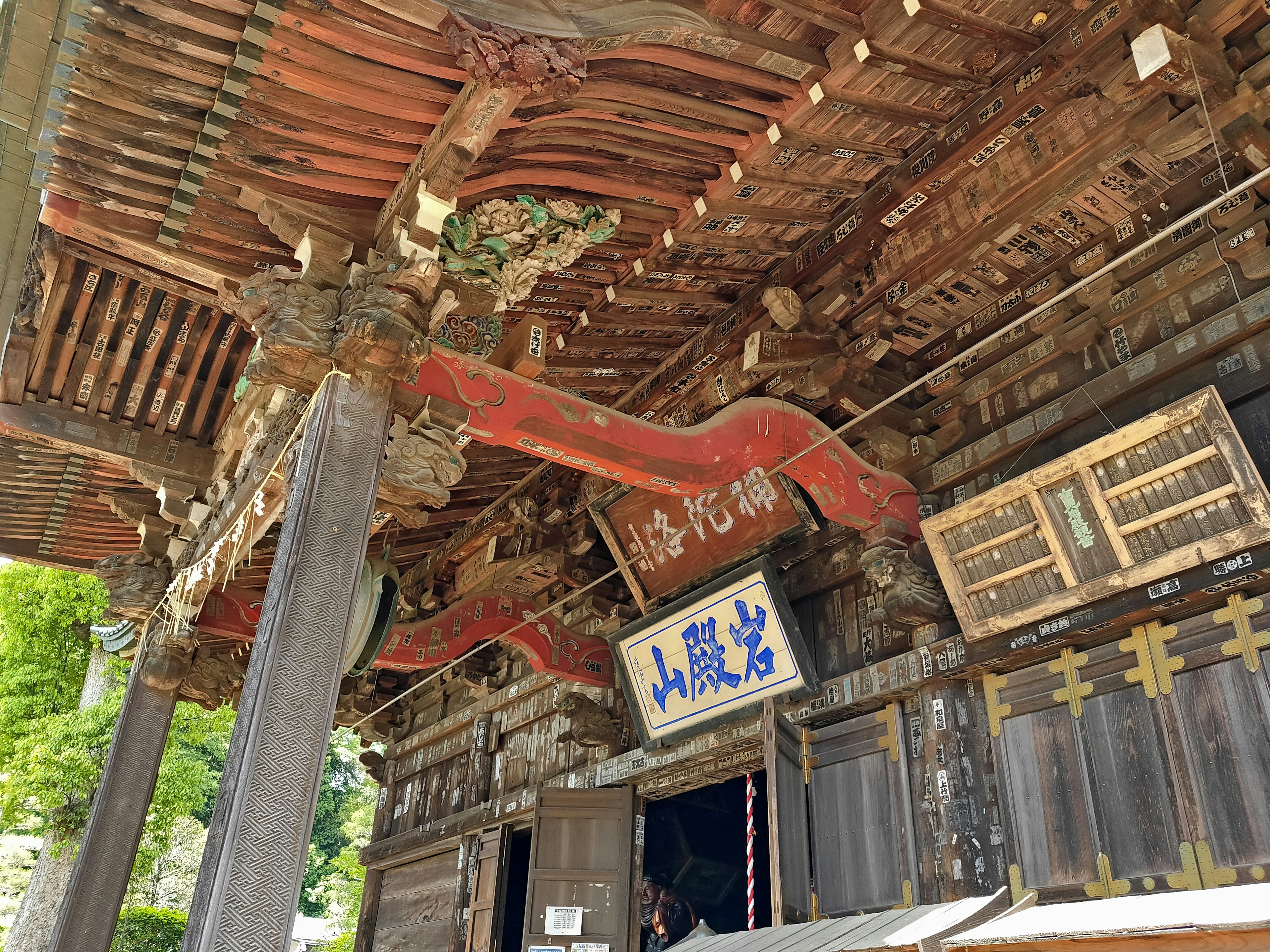 Entrance of an ancient building featuring red decorative beams and wooden doors