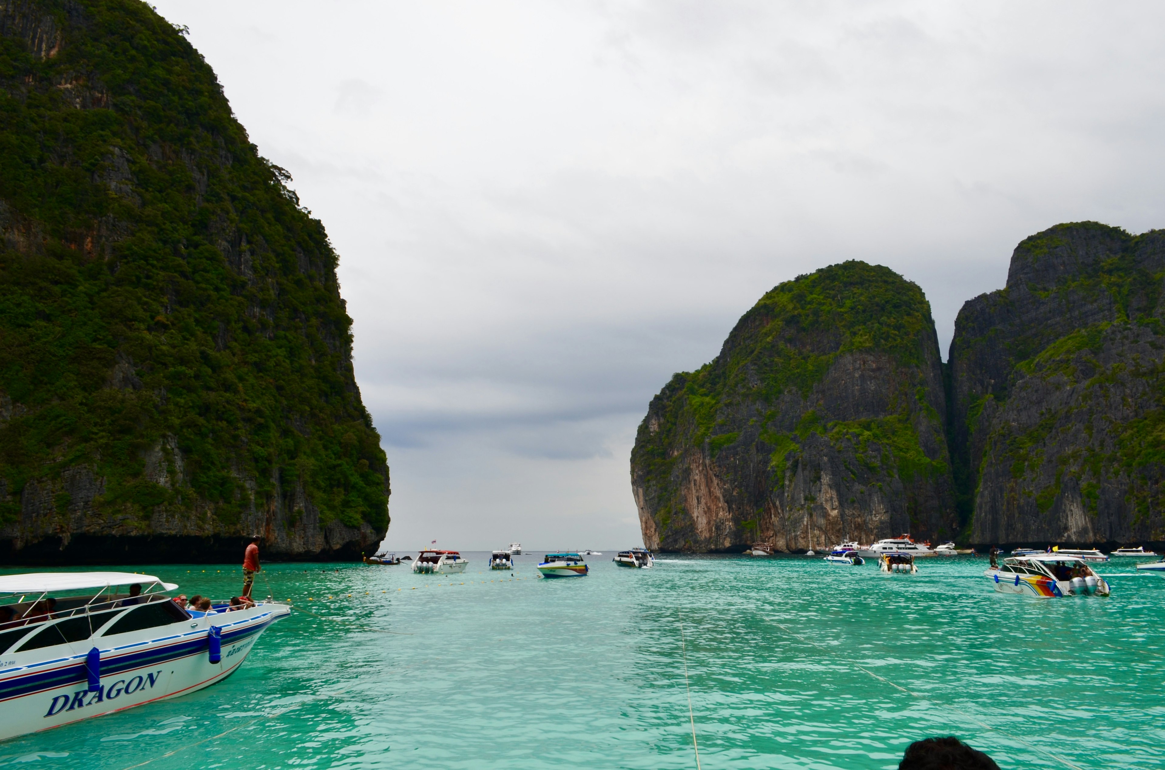 Scenic view of boats in turquoise water surrounded by large rocky cliffs