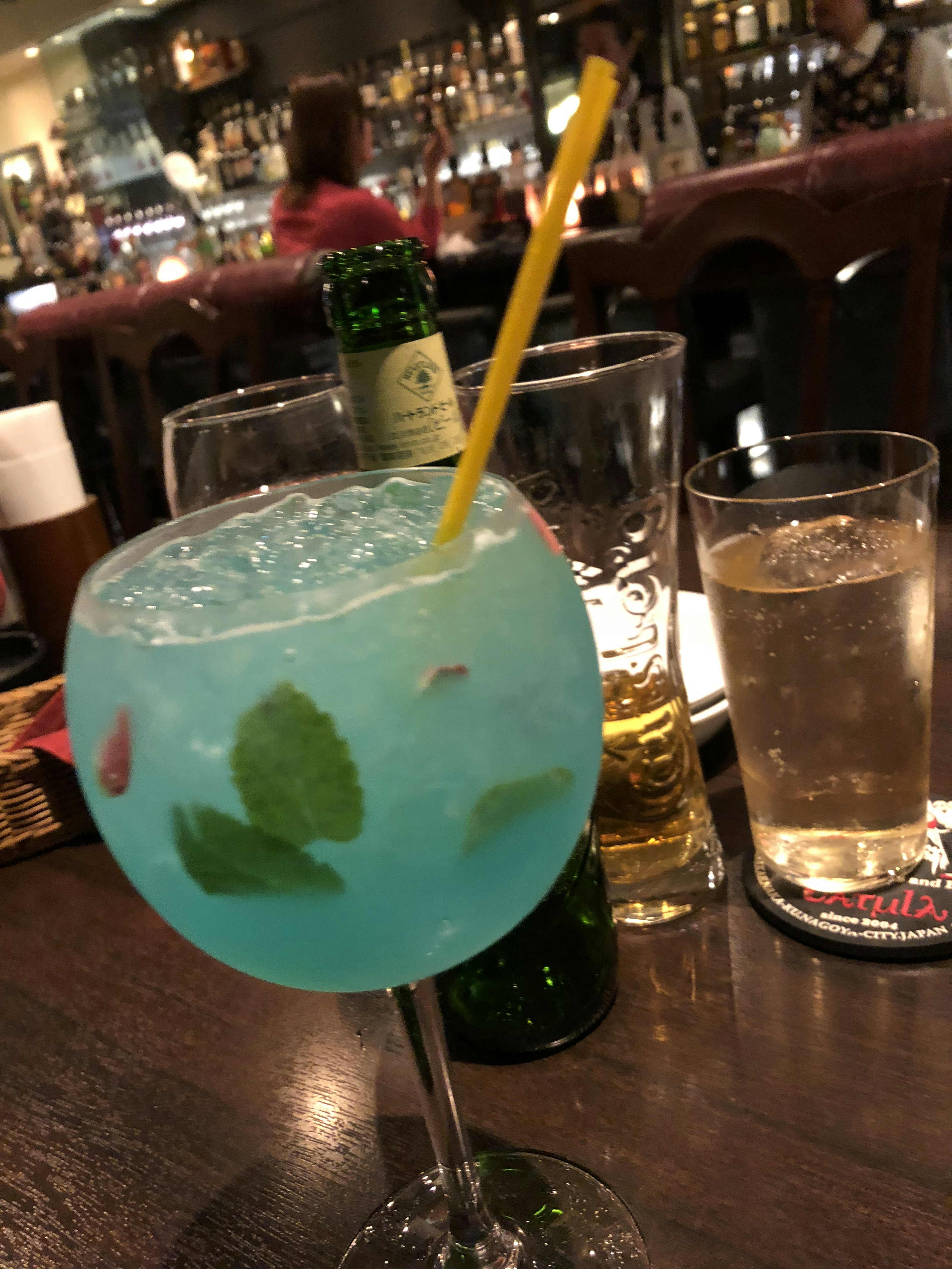 Ein blauer Cocktail in einem Glas mit Minzblättern und Eis