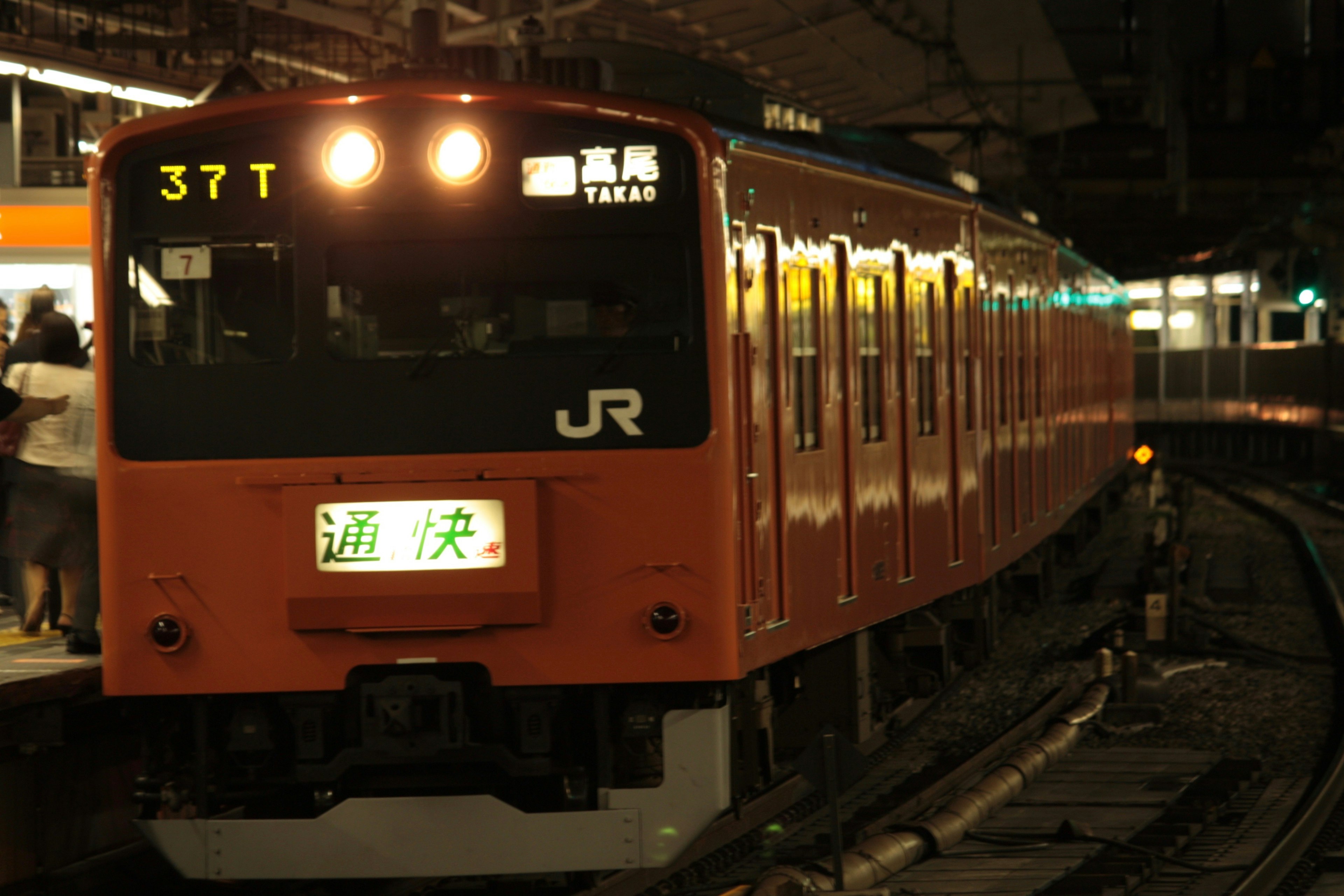 夜の駅に停車中のJRのオレンジ色の電車