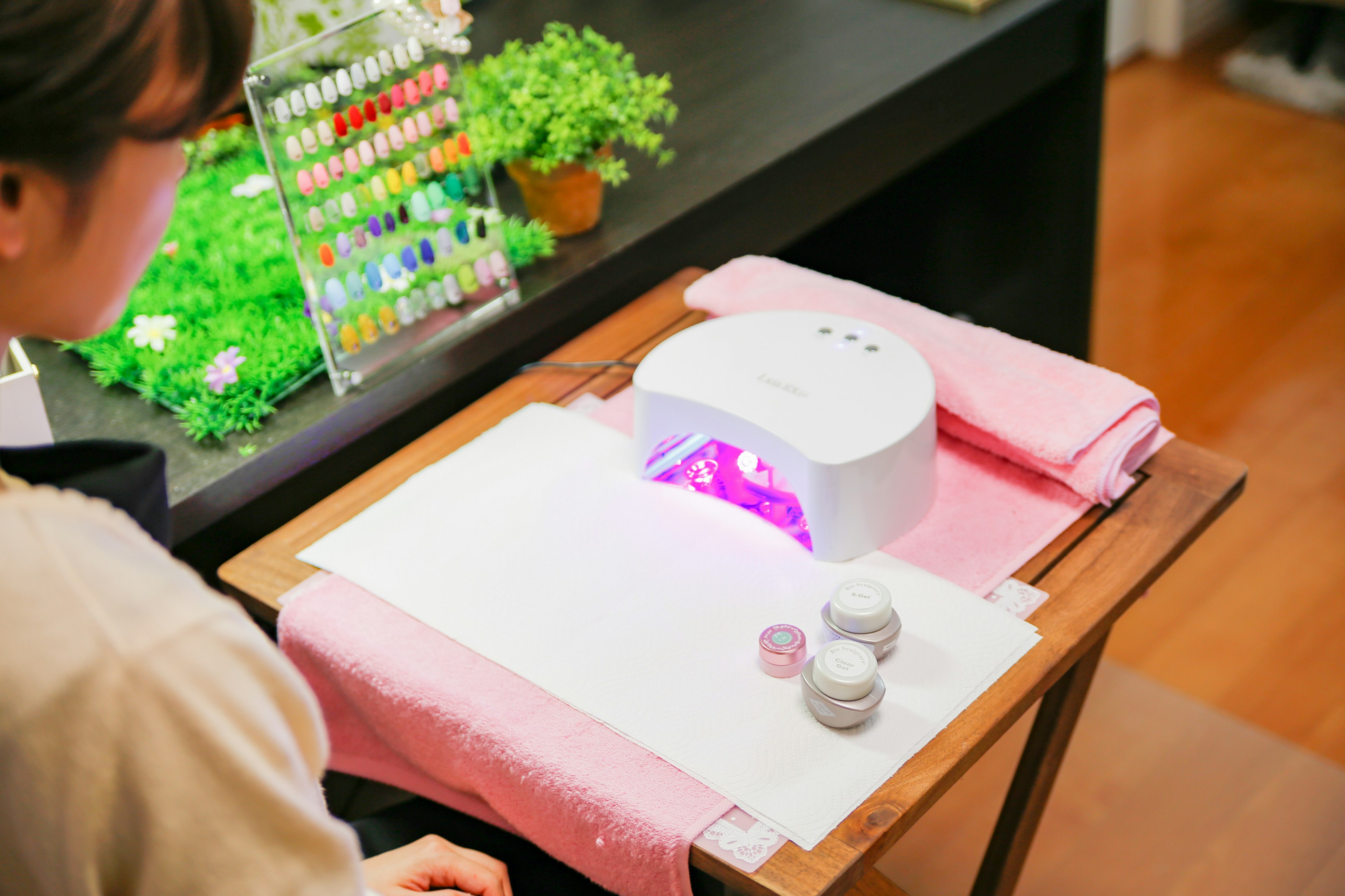 Mujer recibiendo tratamiento de uñas en gel con lámpara UV en un salón de uñas