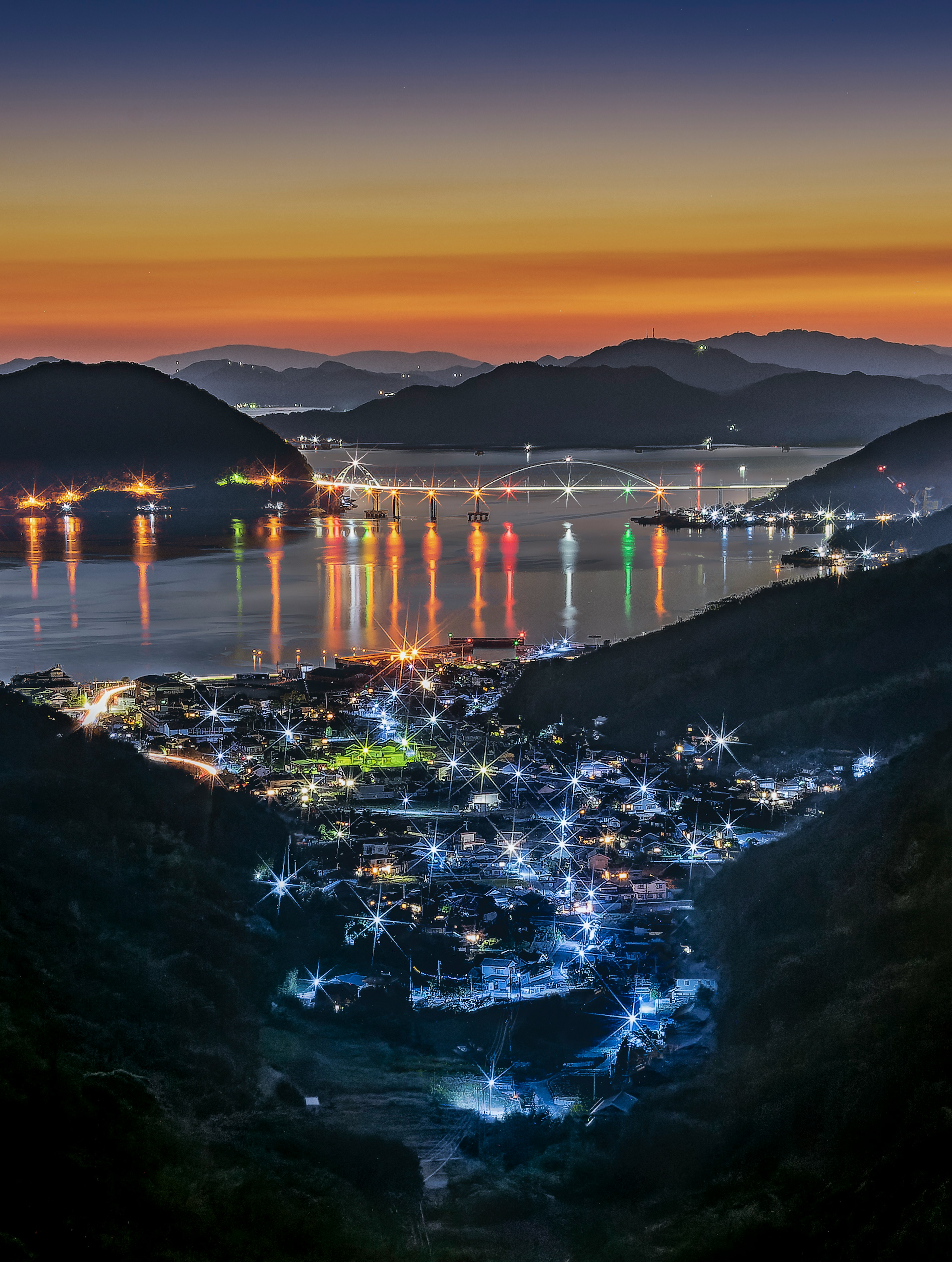 Vue pittoresque d'une ville côtière au crépuscule avec des lumières colorées se reflétant sur l'eau