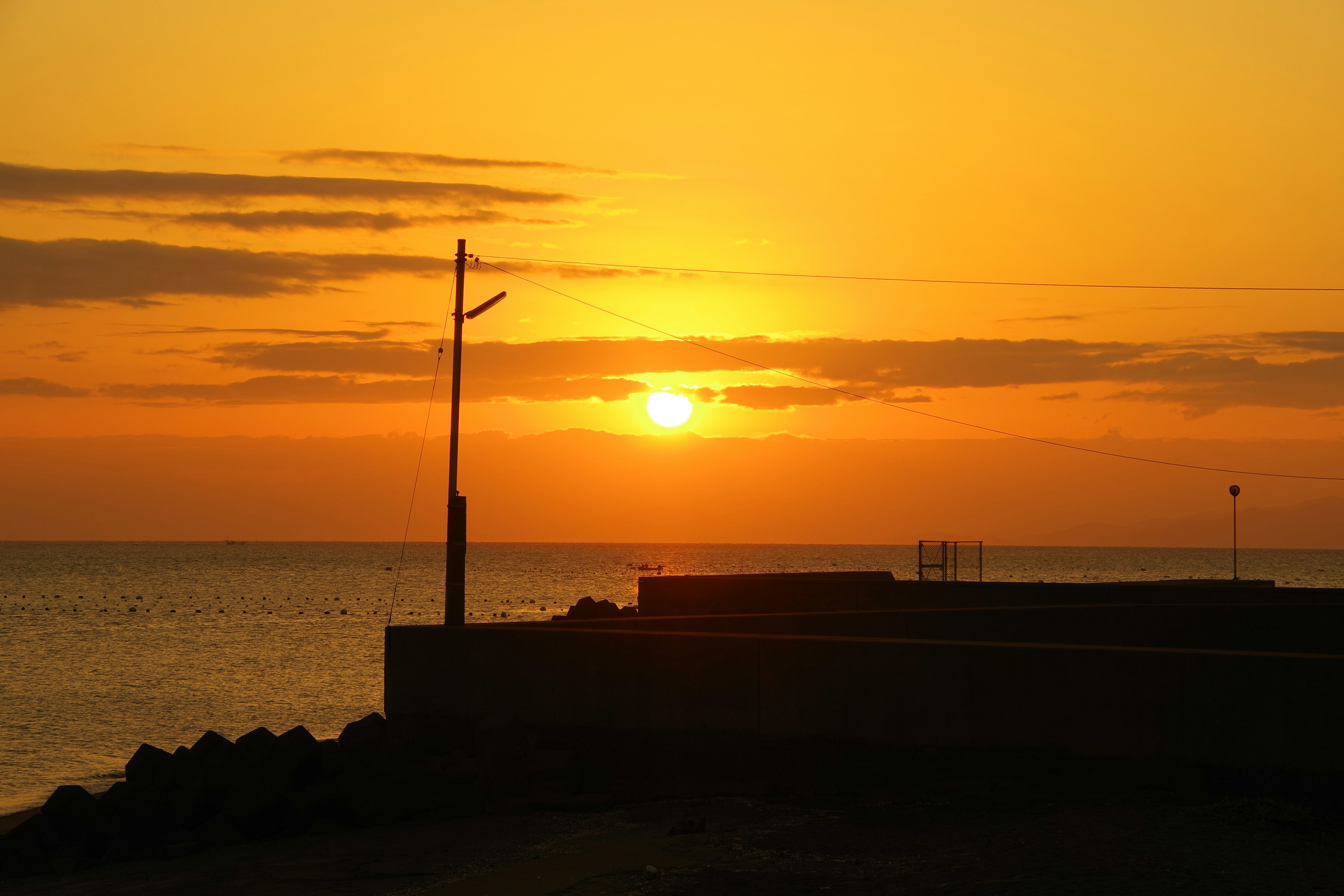 Schöner Sonnenuntergang über dem Meer mit silhouettierten Strukturen