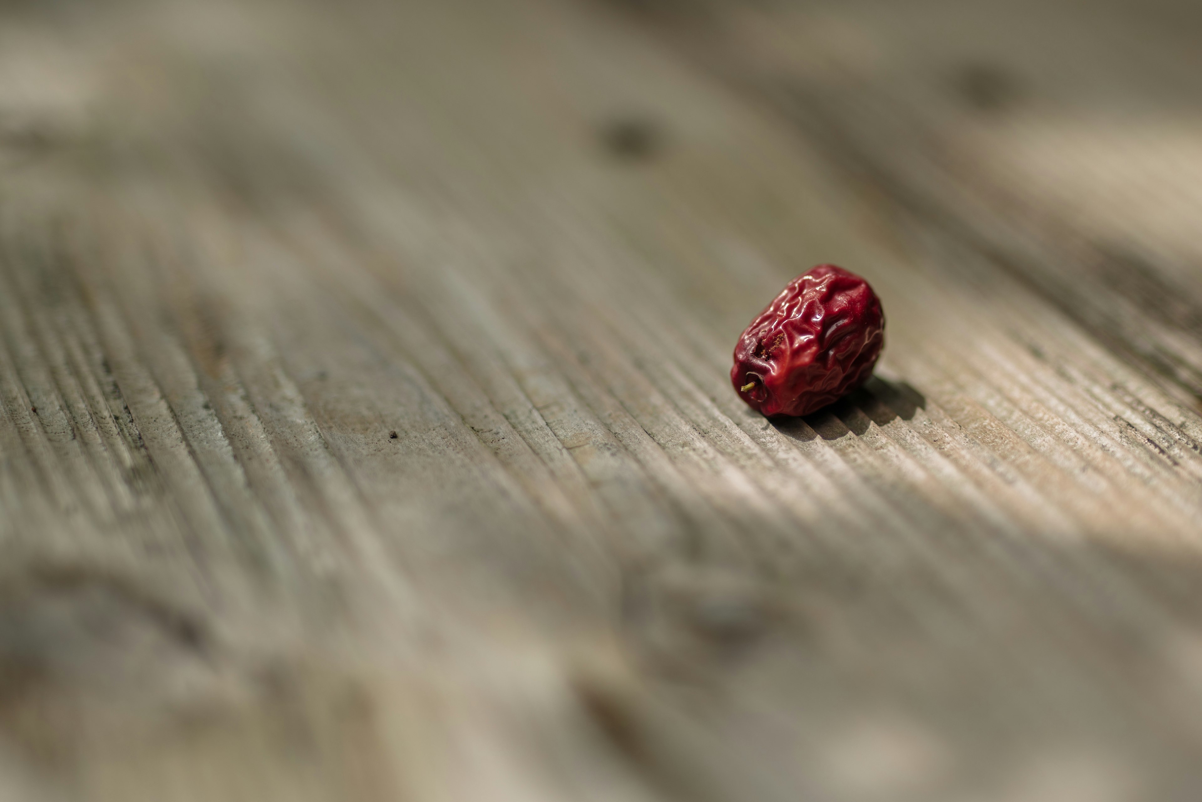 Una fruta roja sobre una mesa de madera