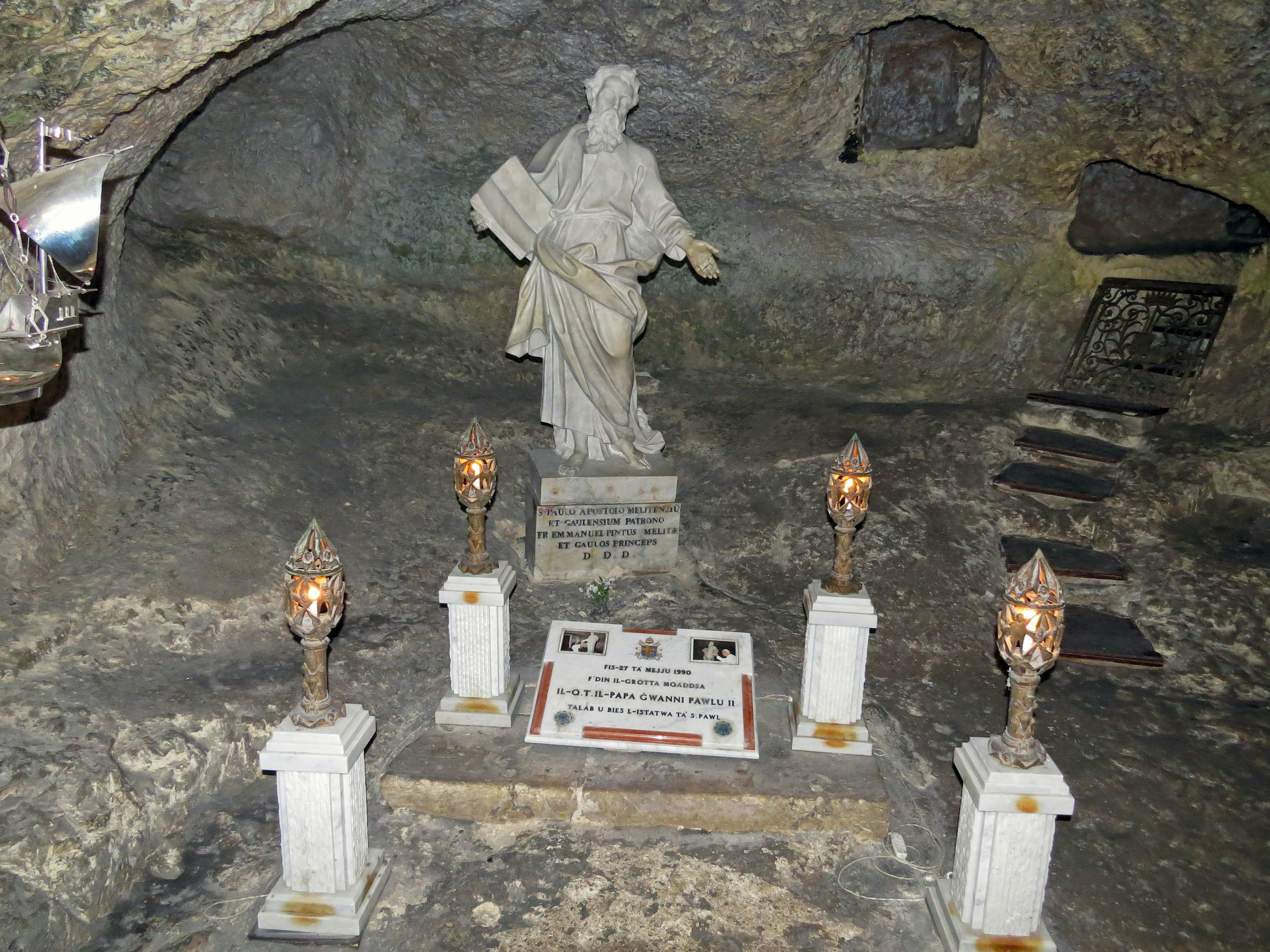 A white statue in a cave with candle arrangements