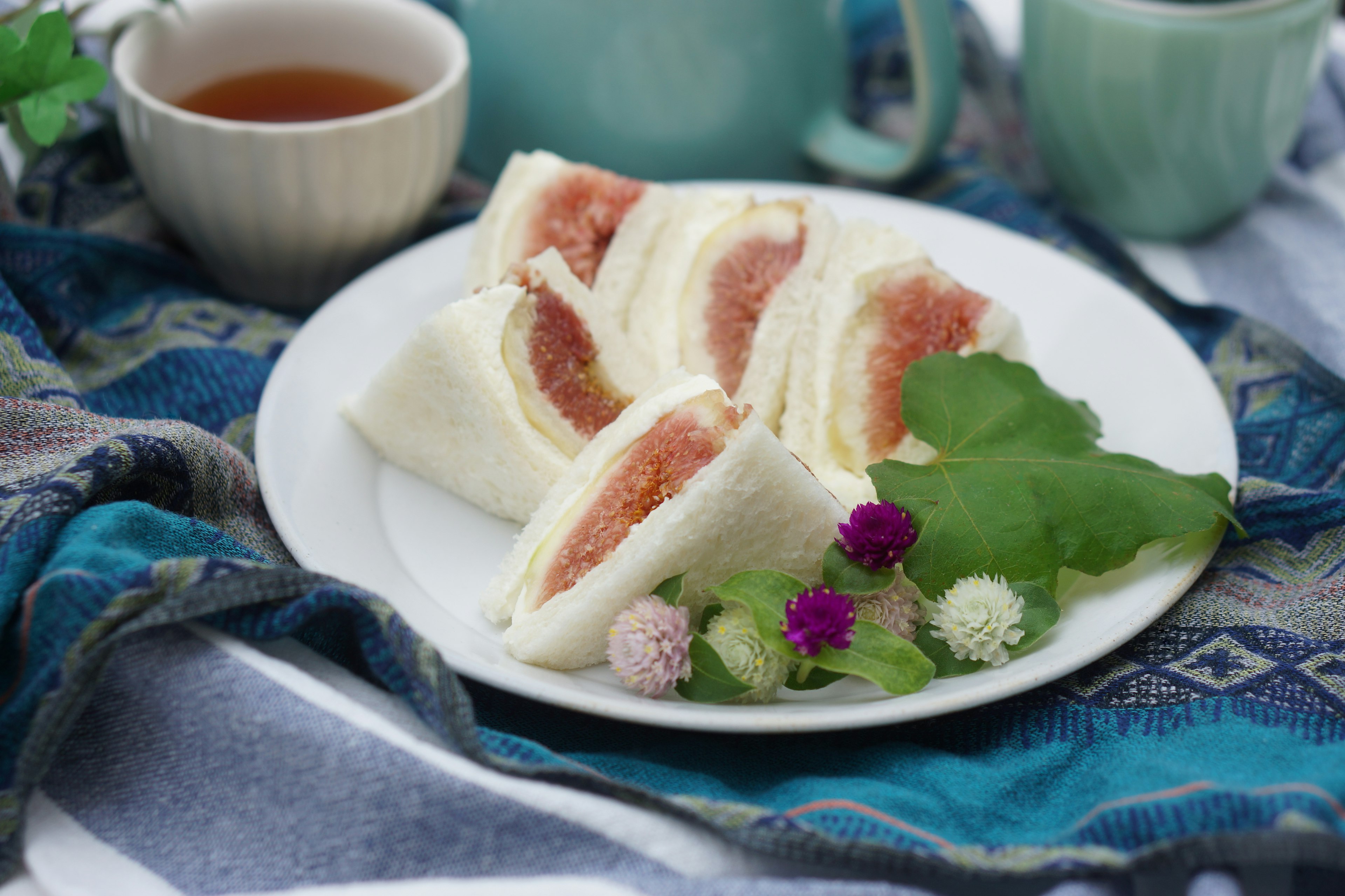 Bollos al vapor rellenos de rodajas de fruta servidos en un plato con hojas verdes y flores