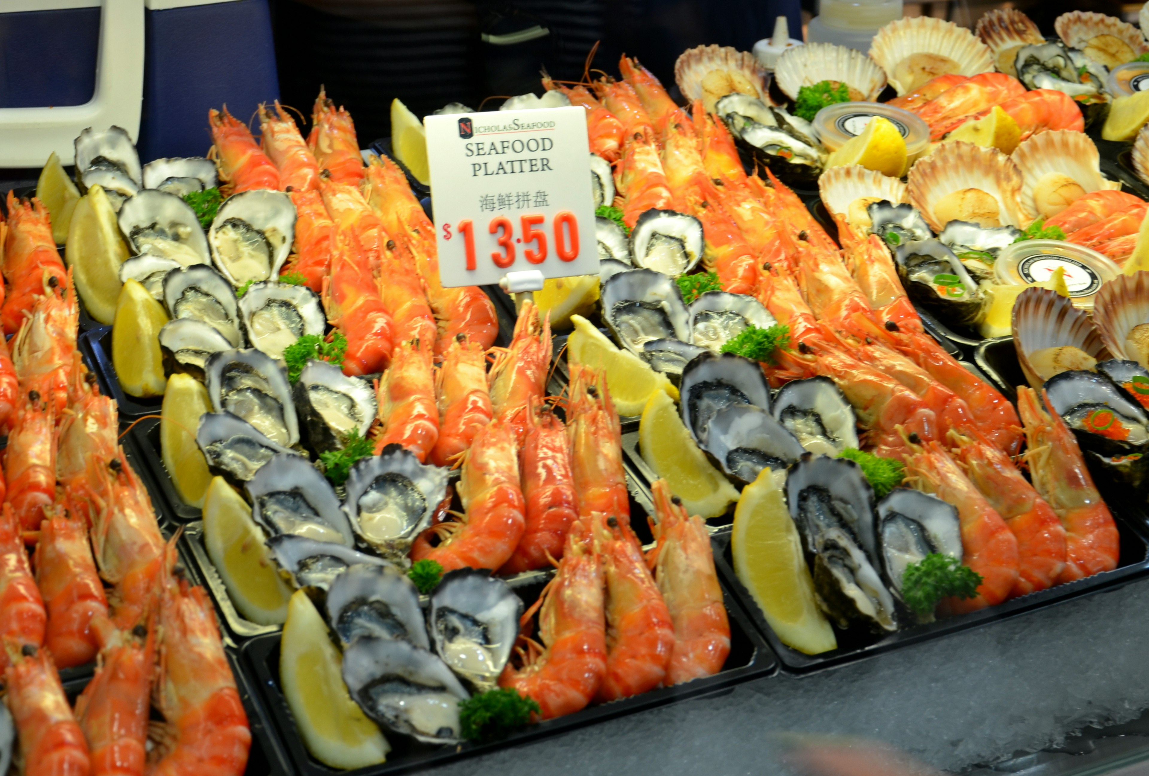 Exhibición vibrante de mariscos en el mercado con camarones y ostras dispuestos en bandejas