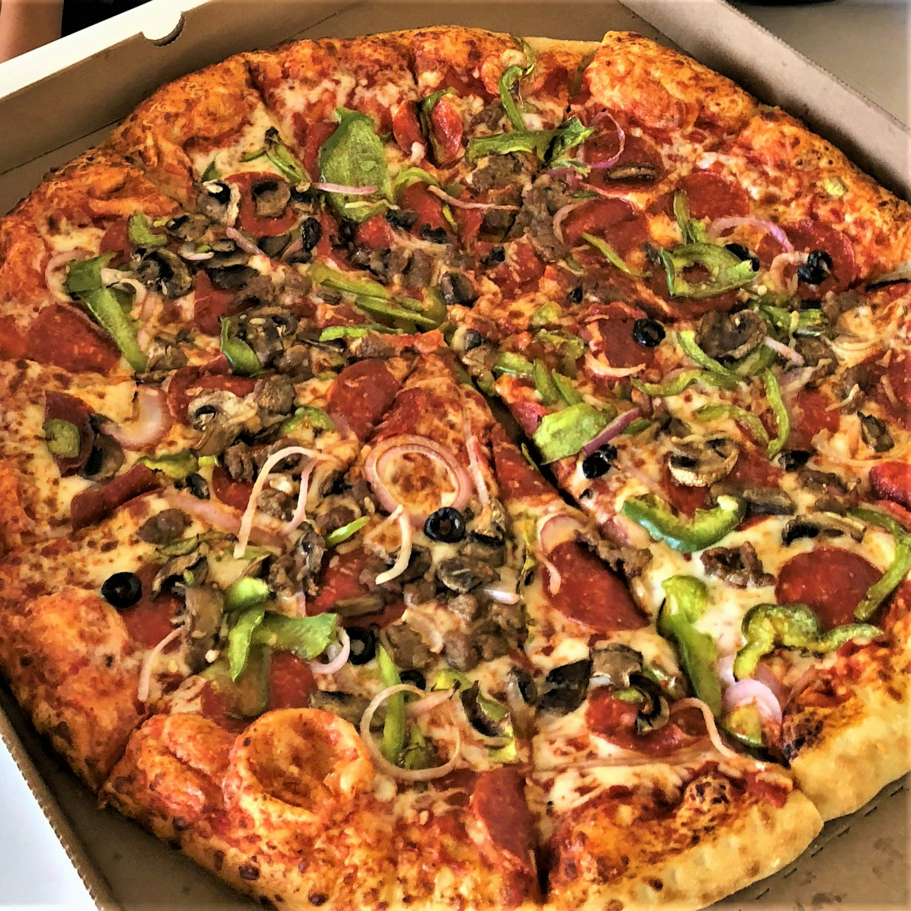 Colorful pizza with various toppings in a takeout box